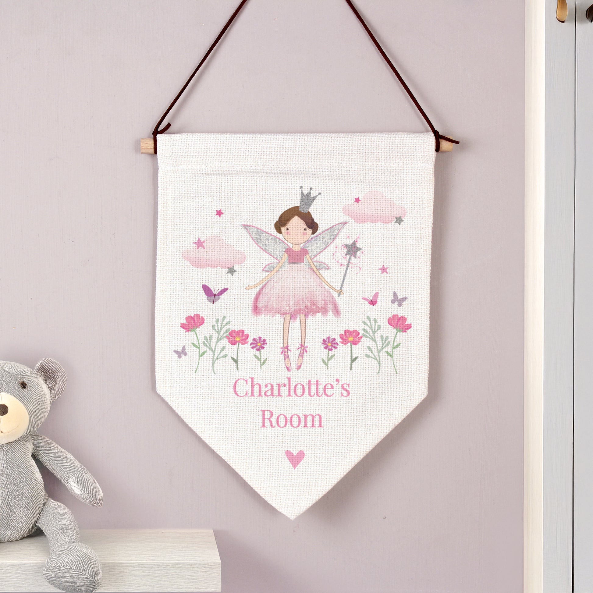 Personalized children's room banner with fairy design and teddy bear on shelf.