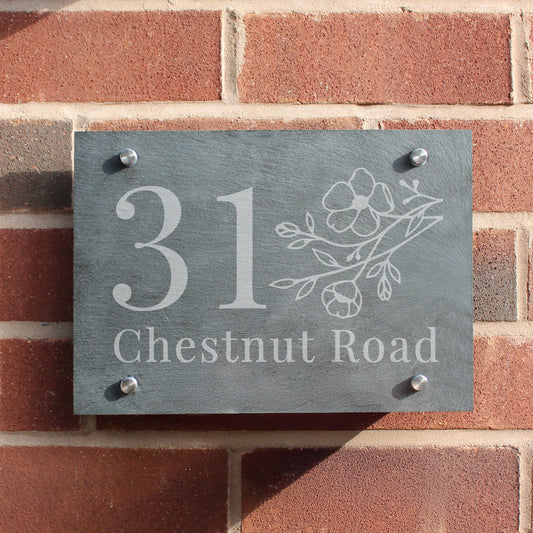 Slate house number sign with floral design on a brick wall
