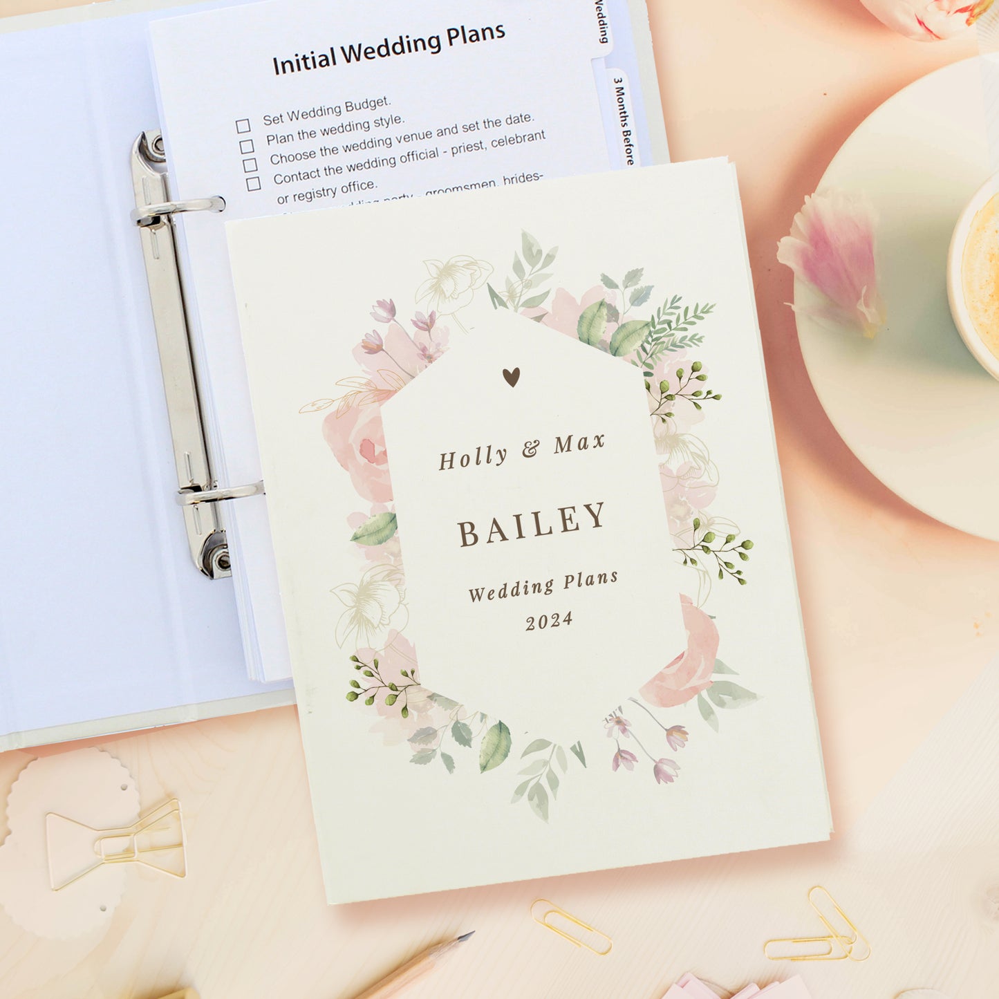 Wedding planning binder with floral design and 'Holly & Max Bailey Wedding Plans 2024' text.