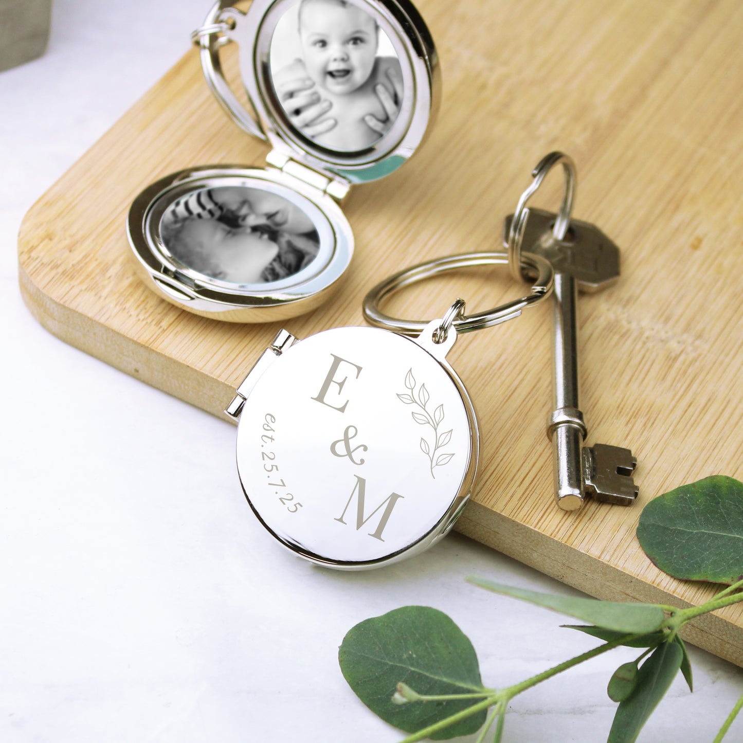 Keychain with engraved initials 'E & M' on a wooden board with a baby photo inside.