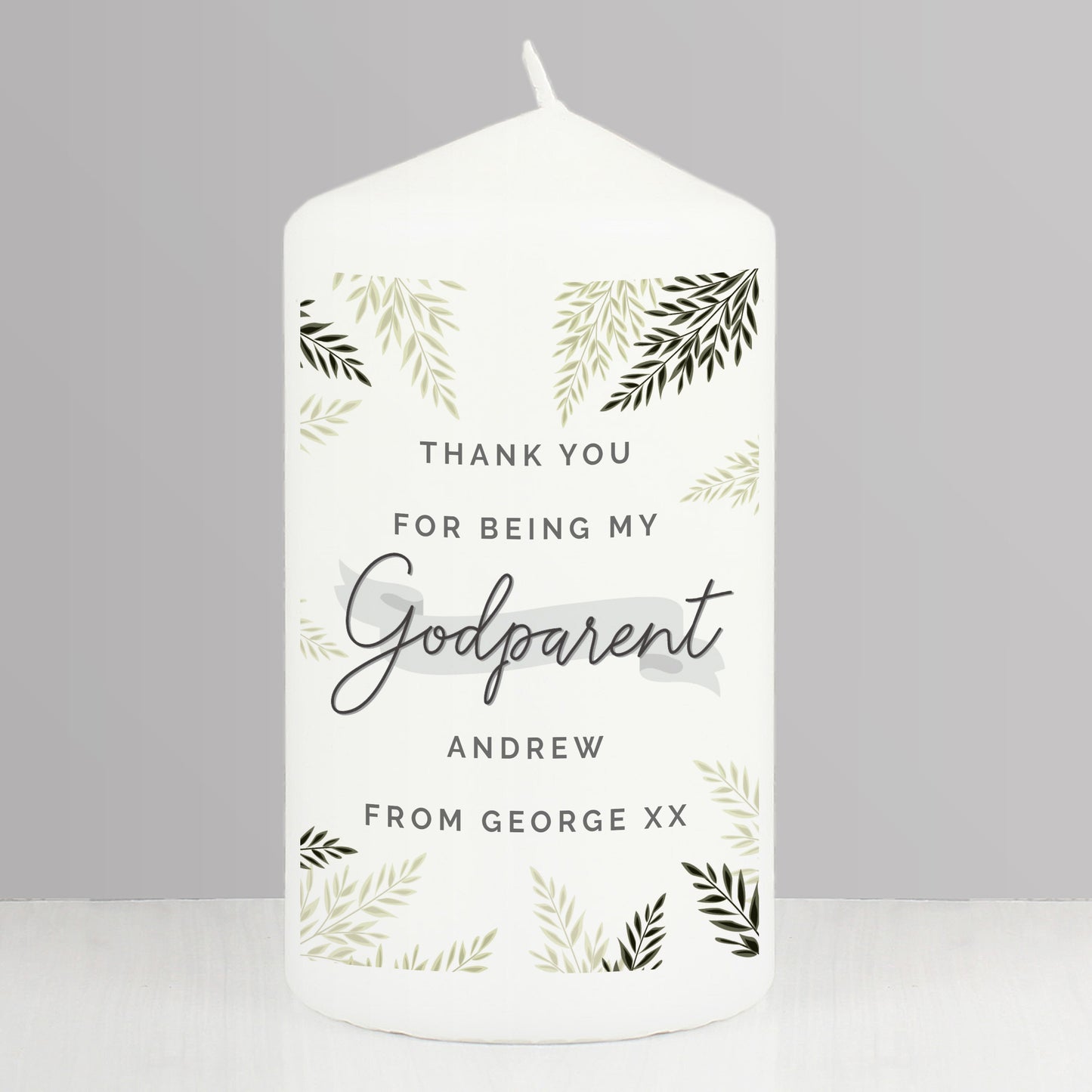 White candle with personalised text and leaf patterns on a grey background