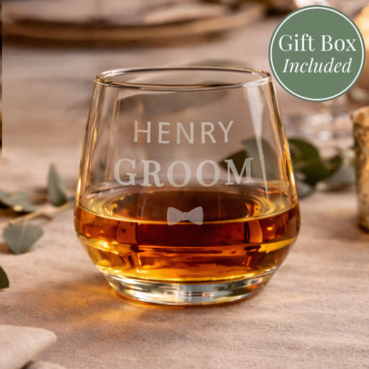 Glass of whiskey with 'HENRY GROOM' engraving on a wooden surface, gift box included.