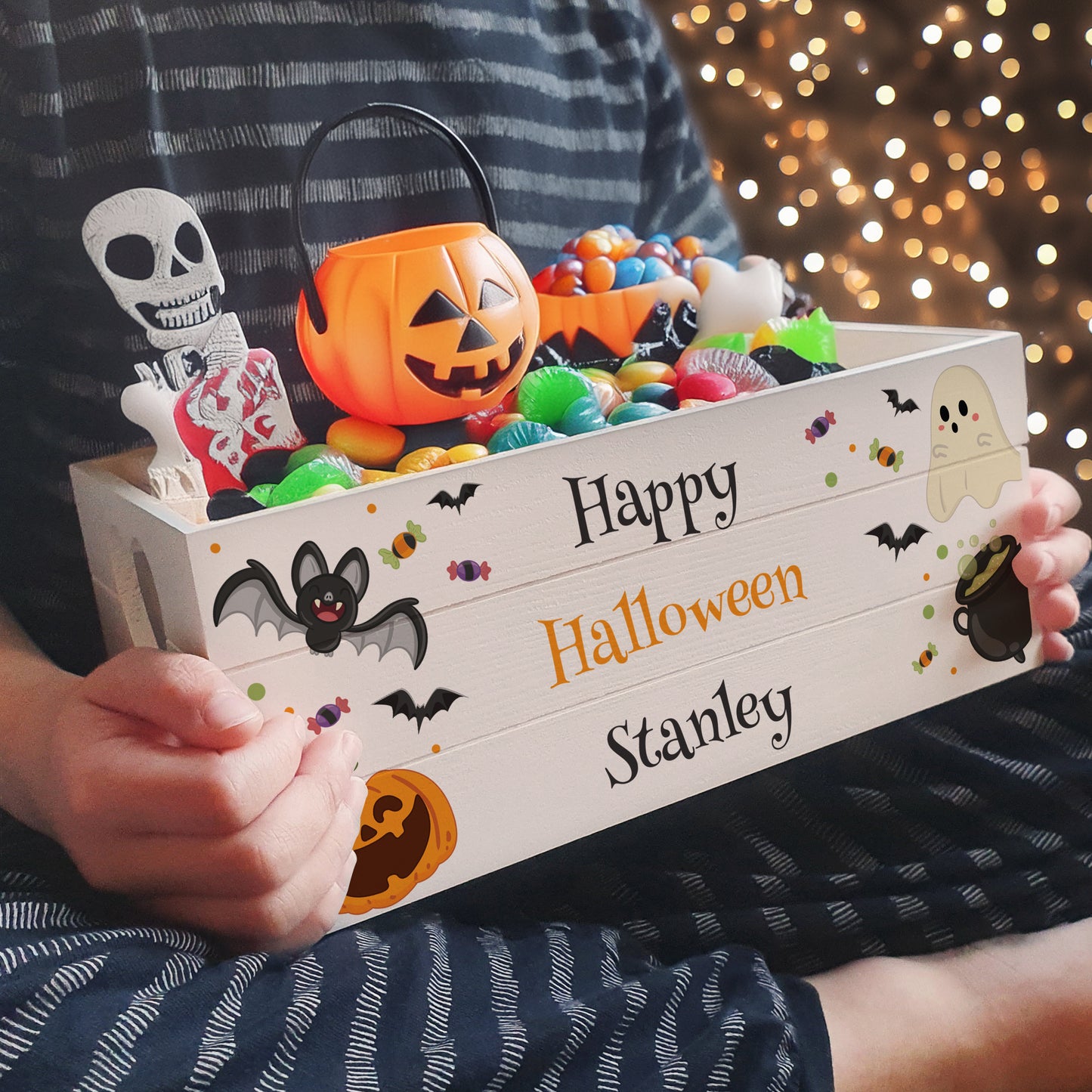 Person holding a personalised Halloween candy box with treats and decorations.