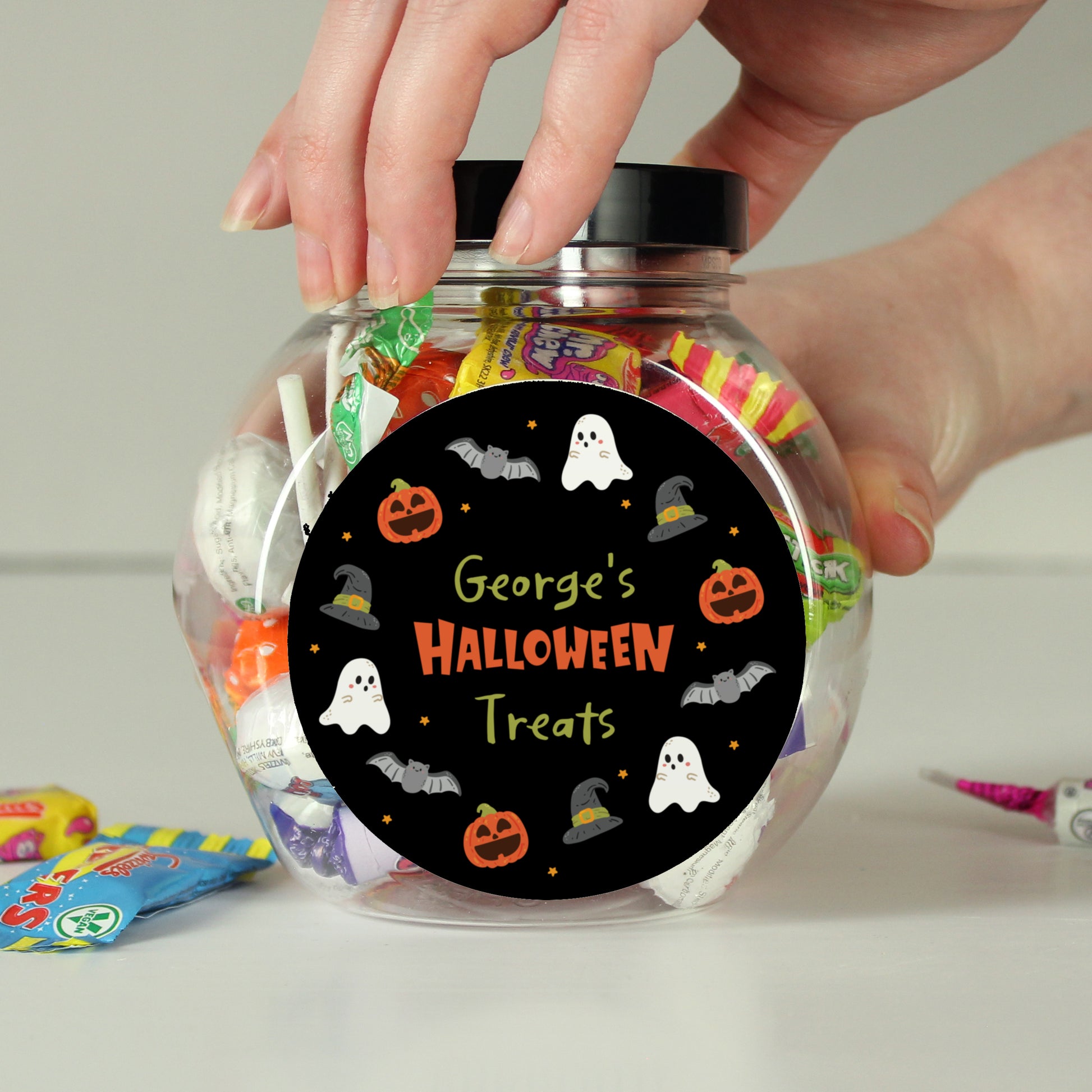 Jar labeled 'George's Halloween Treats' with colorful candy inside, held by a hand.