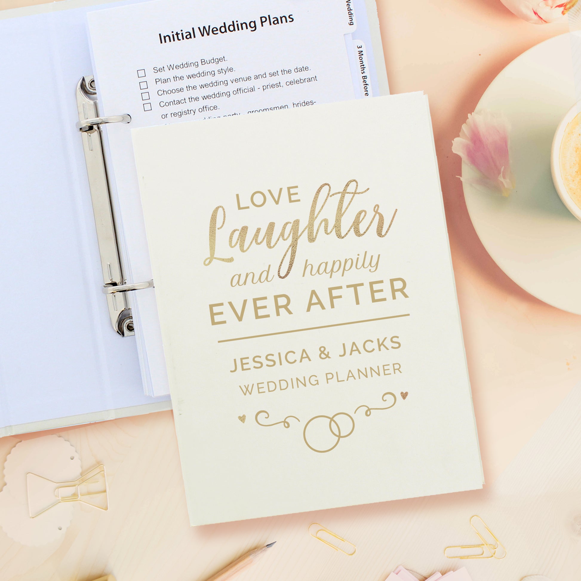 Wedding planner book titled 'Love, Laughter, and Happily Ever After' with stationery items on a light background.