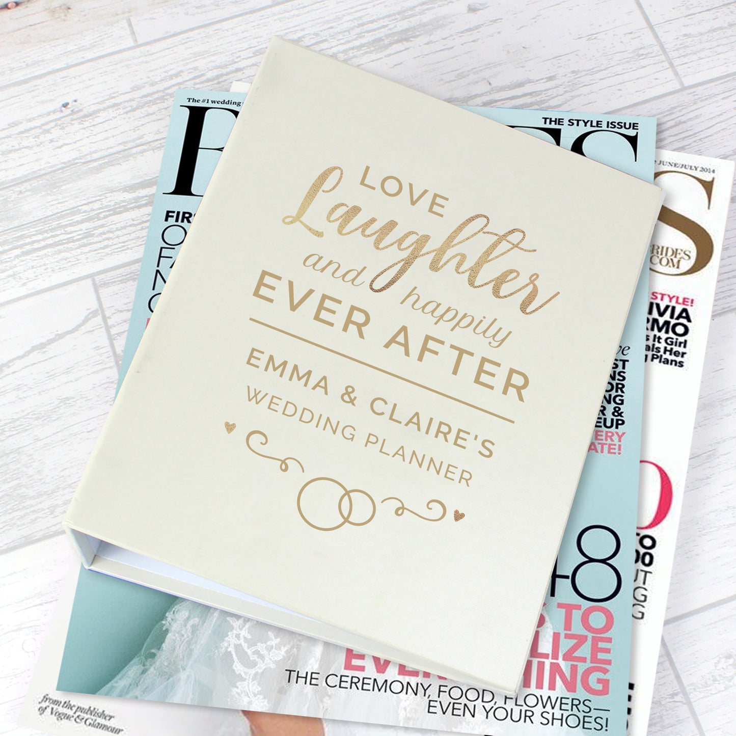 Wedding planner book titled 'Love, Laughter and Happily Ever After' on top of magazines.