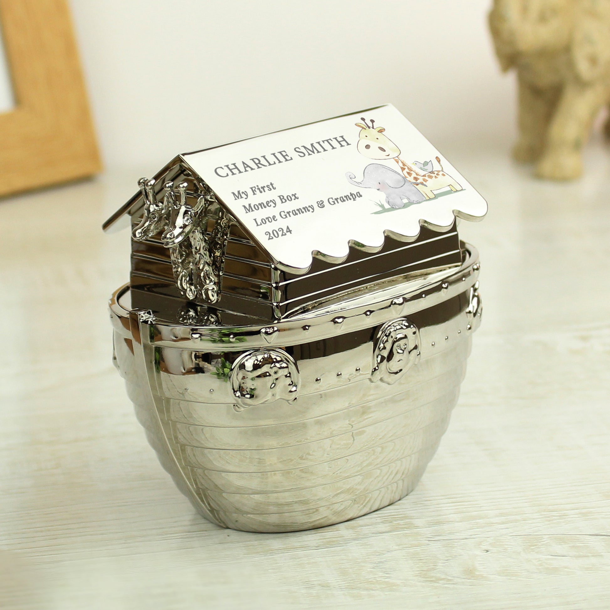Silver nickel hessian friends Noah's Art money box with birth details. Shown on a shelf with numbered blocks, an elephant and a frame.