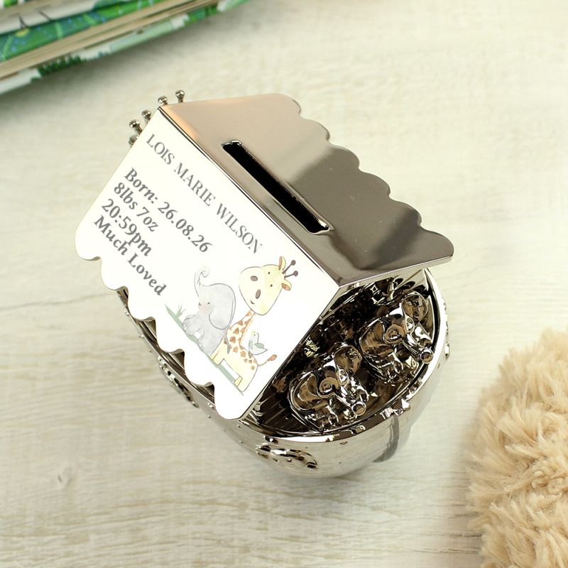 Silver nickel hessian friends Noah's Art money box with birth details. Shown on a shelf with a book.