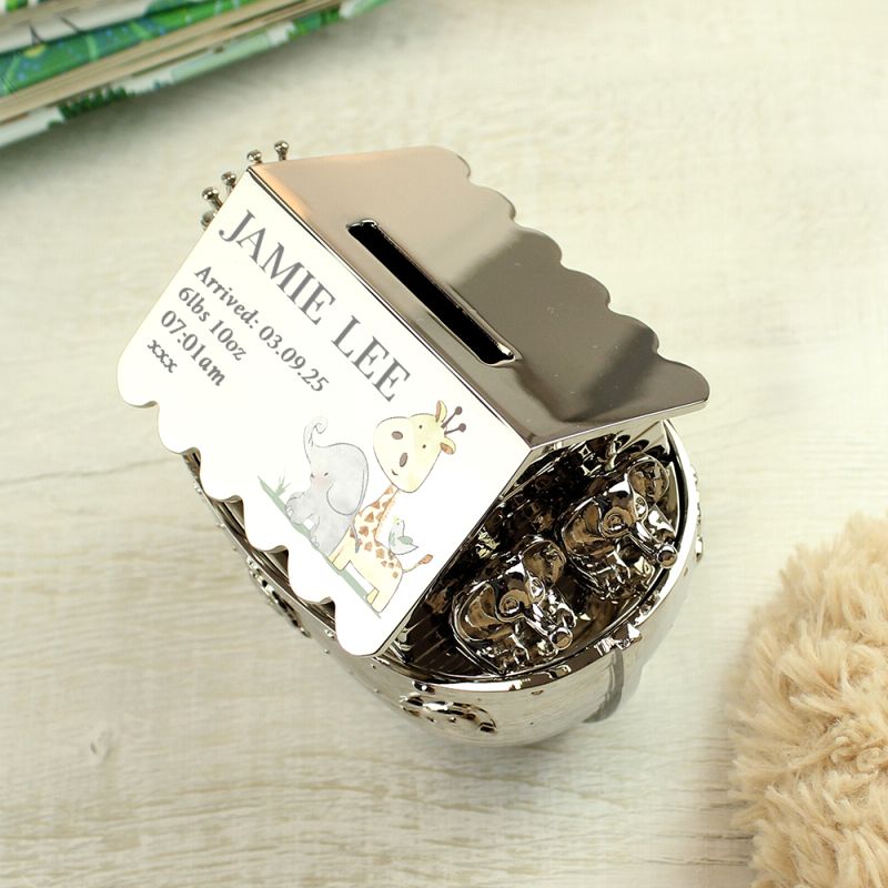 Silver nickel hessian friends Noah's Art money box with birth details. Shown on a shelf with a book.
