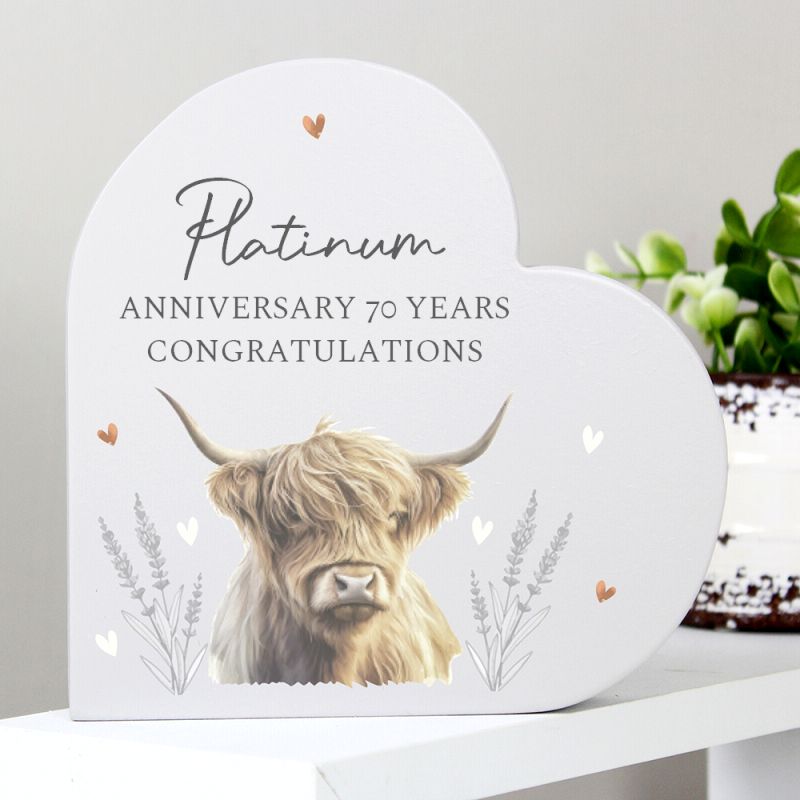 Heart shaped plaque with a highland cow illustration and 'Platinum Anniversary 70 Years Congratulations' text on a white surface.