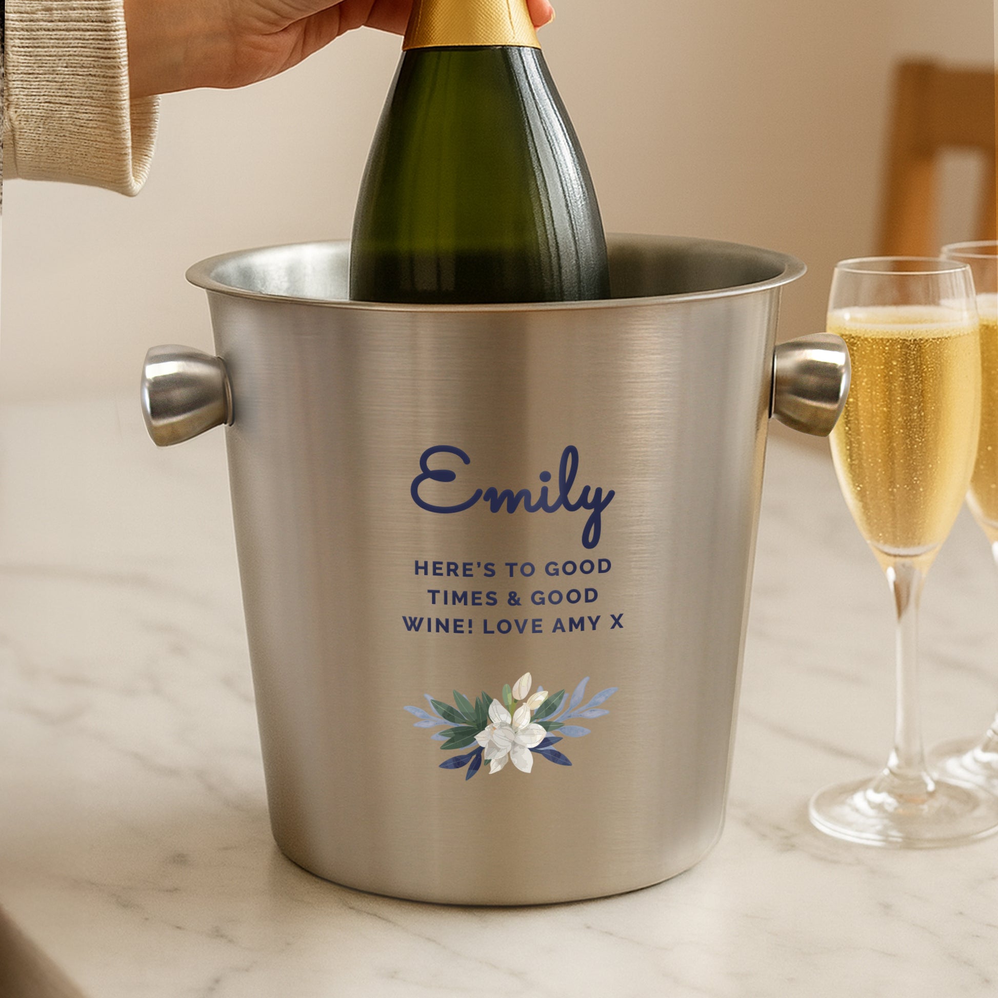 Person pouring champagne into a personalised wine cooler with text and floral design.