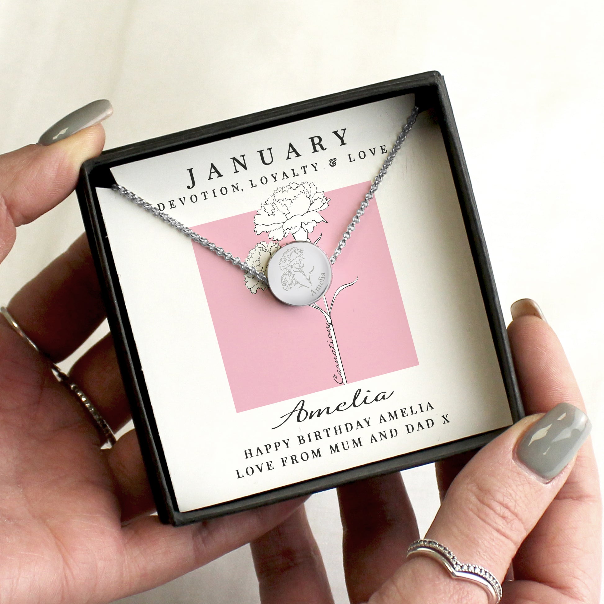 Necklace in a box with a backing card labelled 'January' held by a hand.