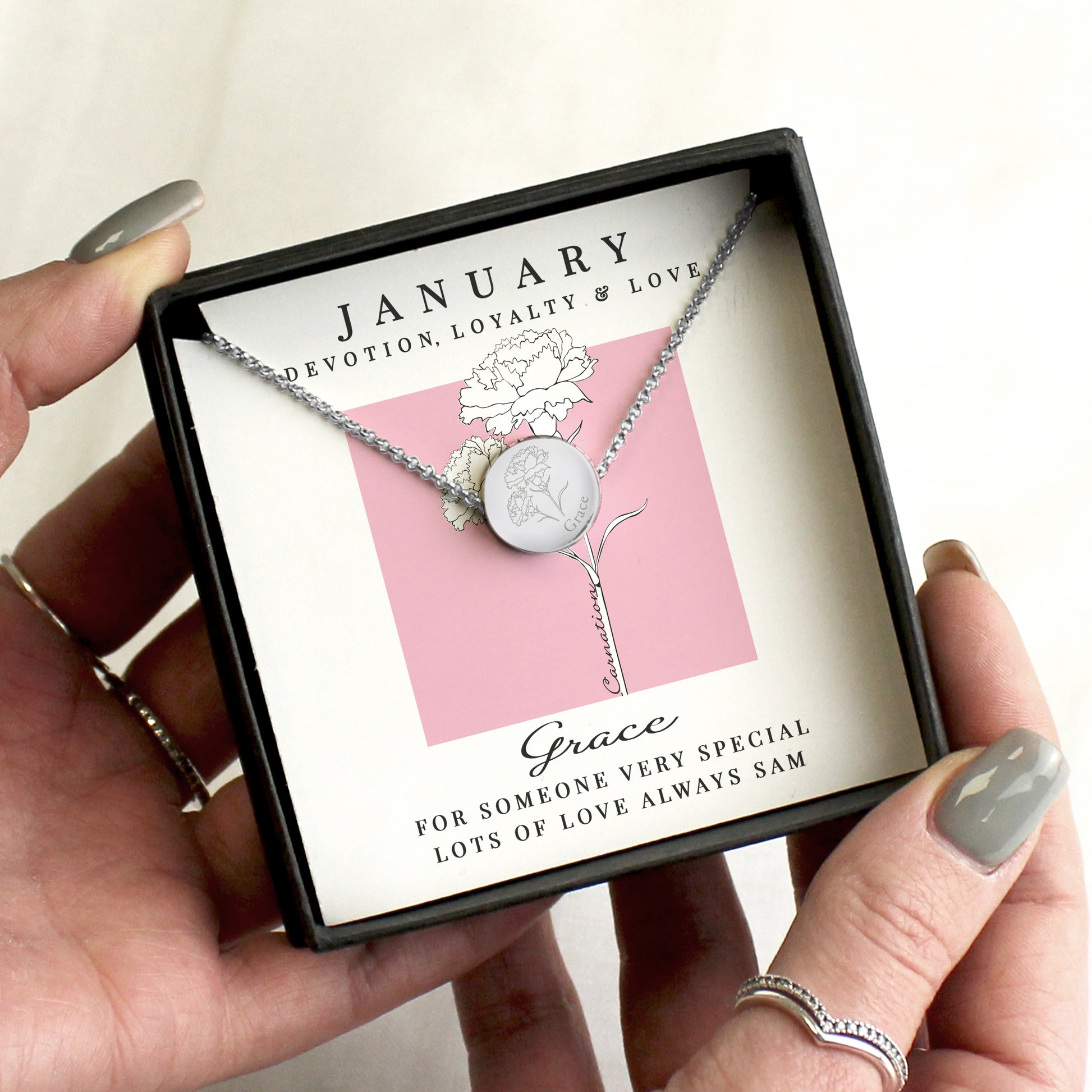 Necklace in a box labelled 'January' held by a hand.