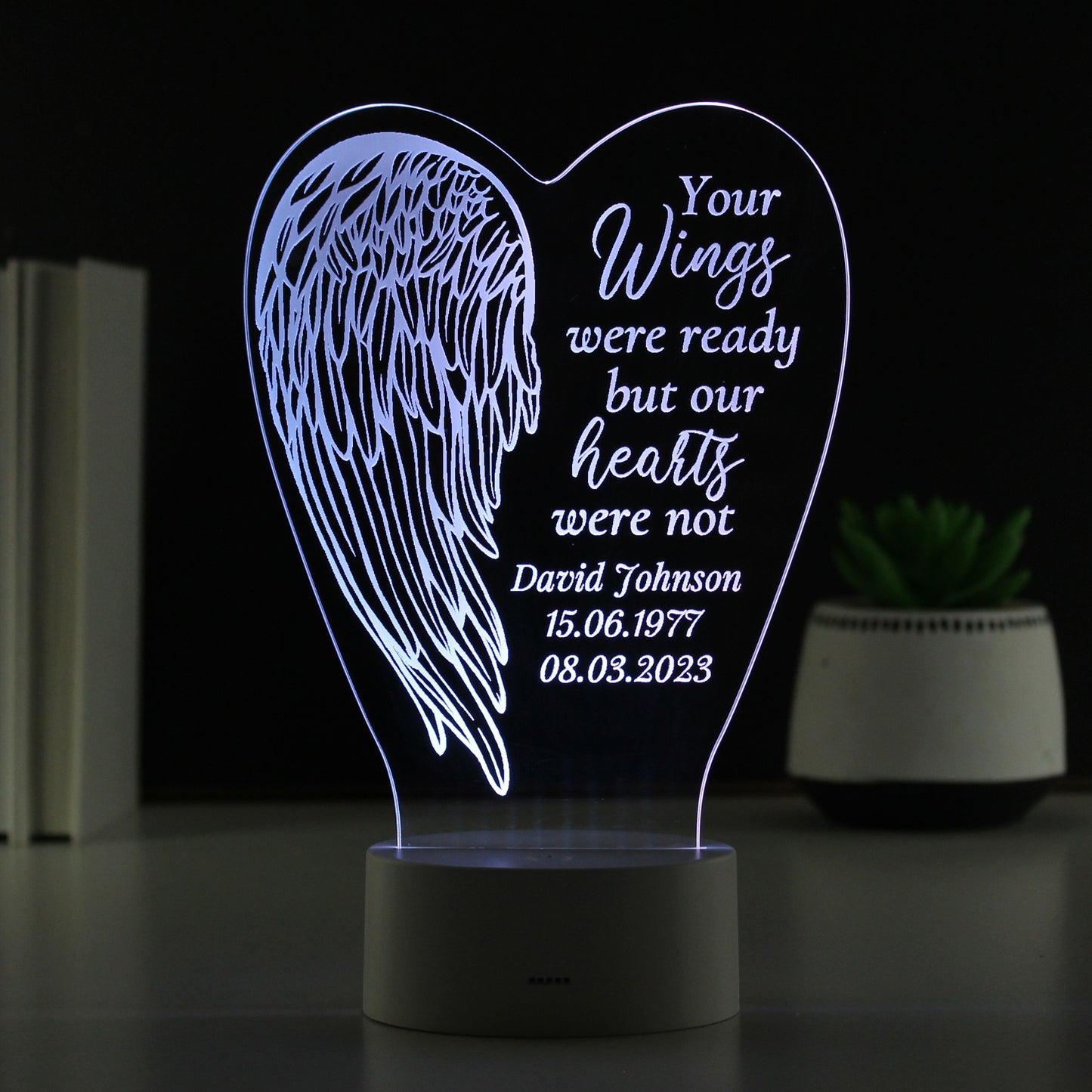 Heart-shaped night light with angel wings and personalised text on a dark background