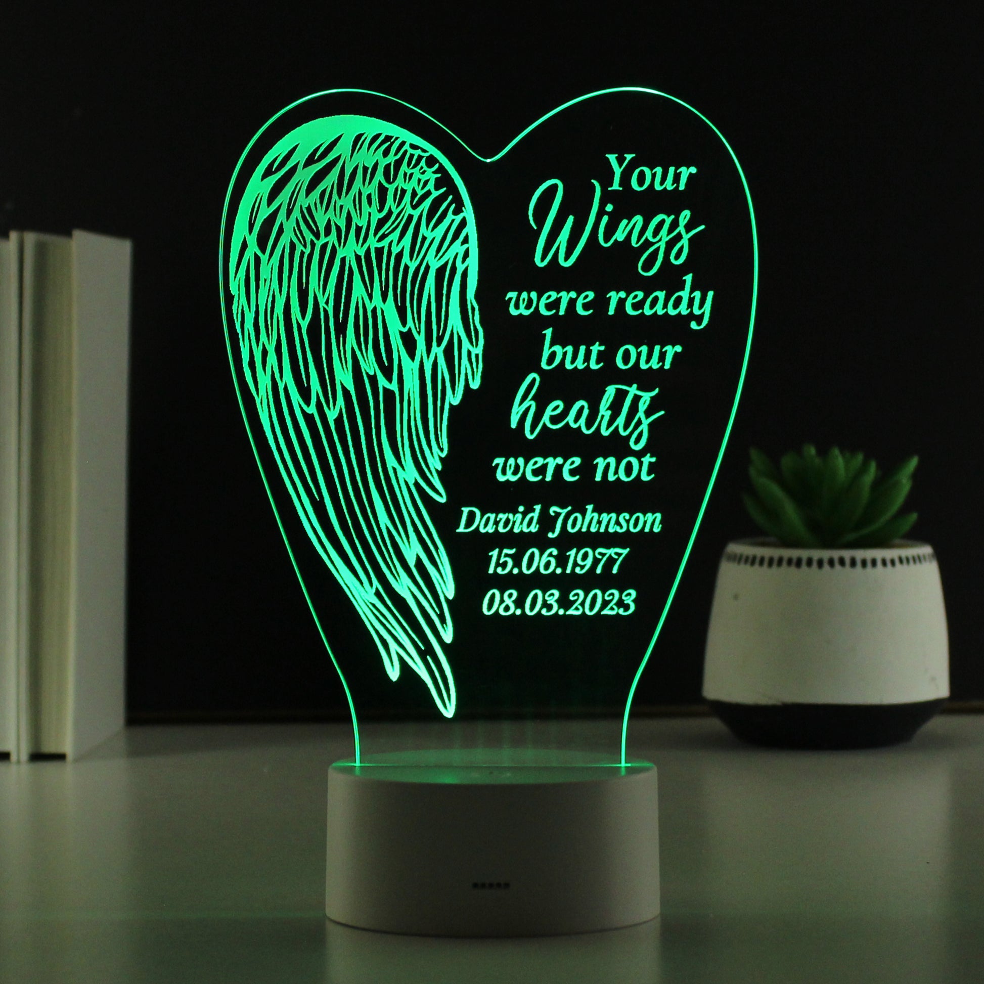 LED lamp with angel wing design and text on a dark background