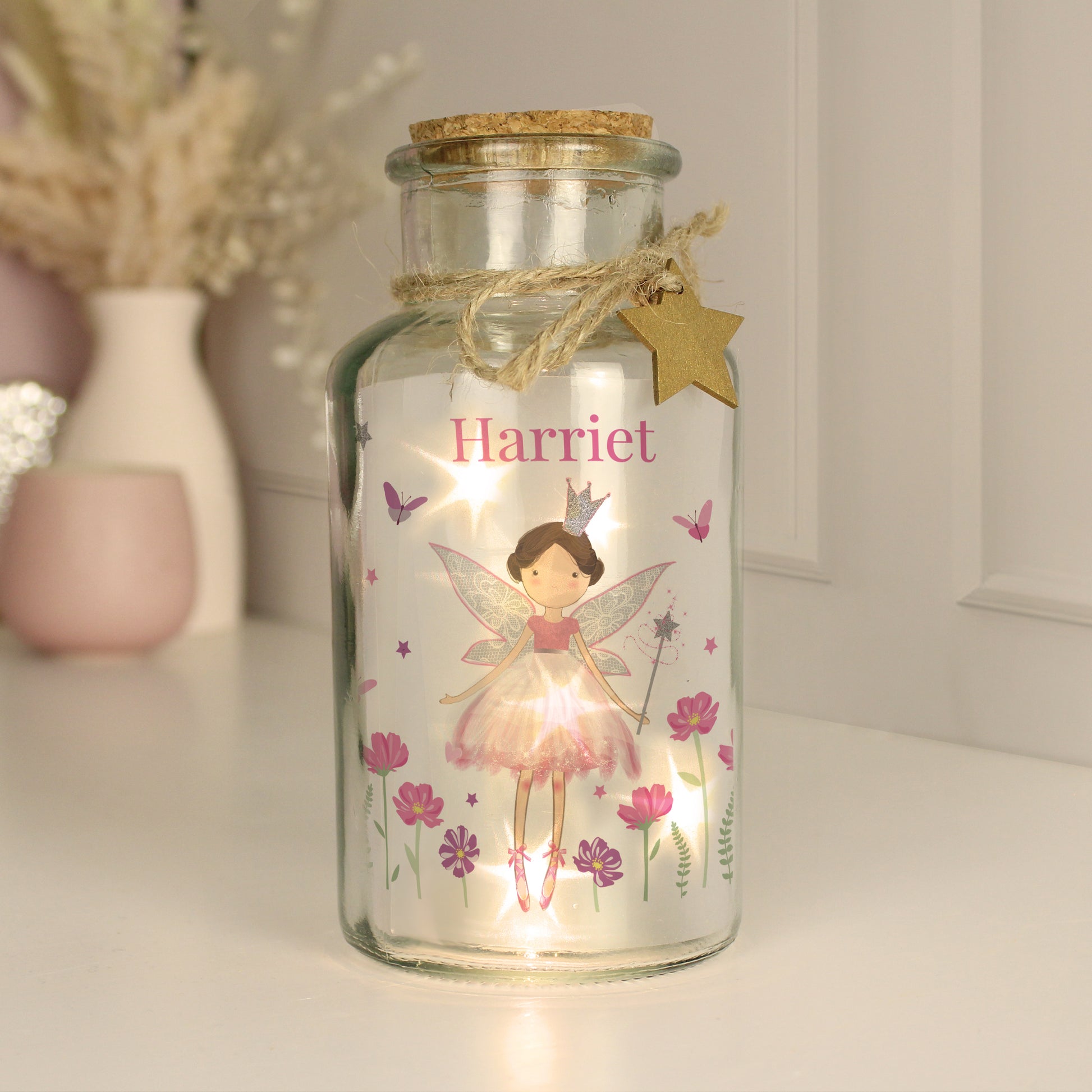 Decorative glass jar with fairy design and 'Harriet' text, featuring a light inside.