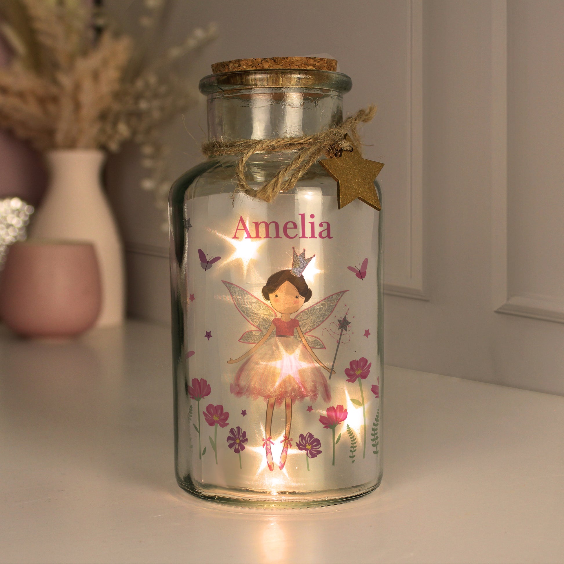 Decorative glass jar with fairy illustration and 'Amelia' text, illuminated from within.