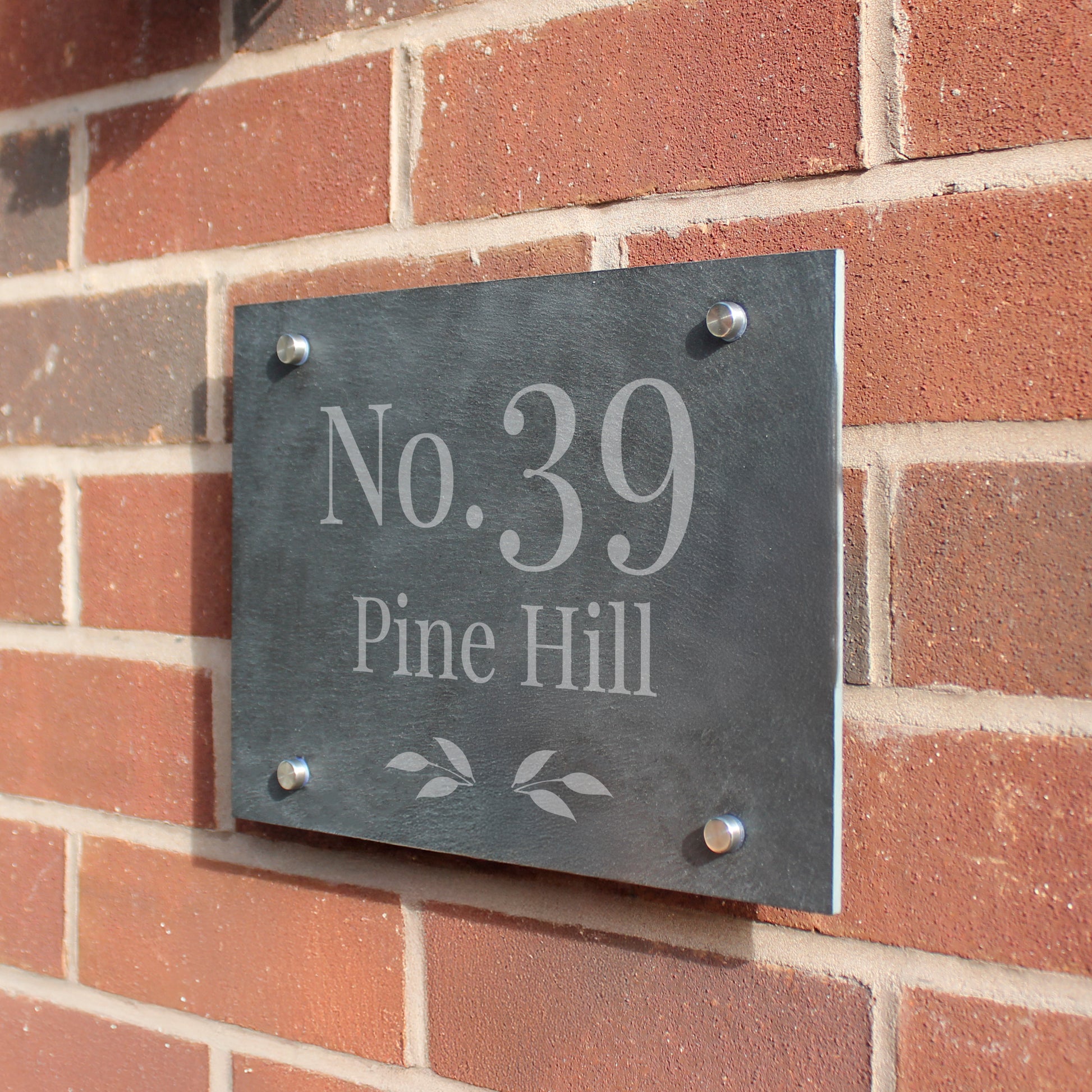 Slate house number sign with 'No. 39 Pine Hill' on a brick wall