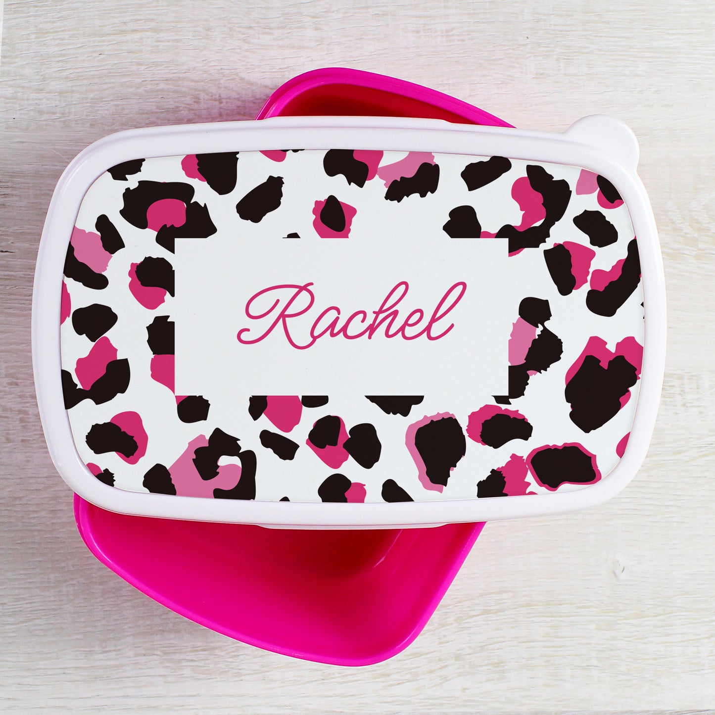 Leopard print lunch bag with pink accents and 'Rachel' name on a light wooden surface
