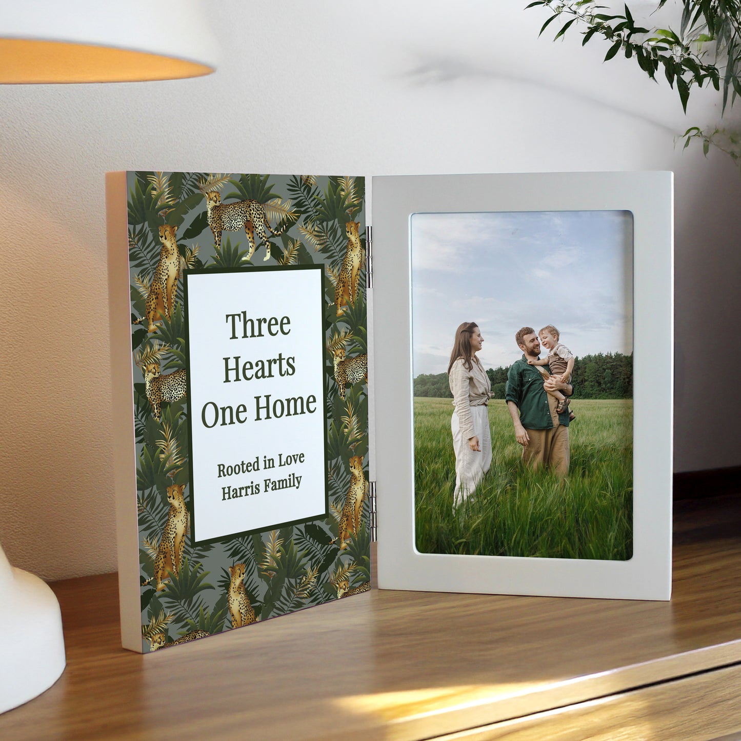 Decorative photo frame with a heart design and a photo of a couple and child on a wooden surface.
