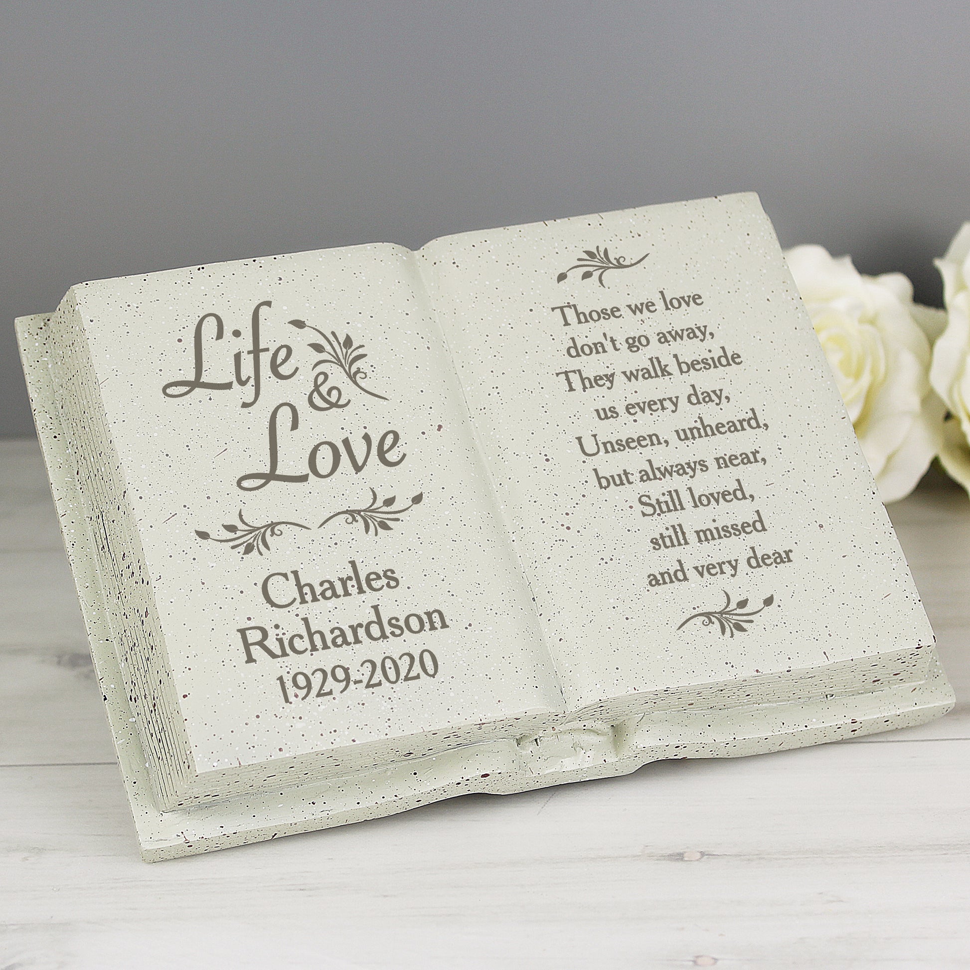 Memorial stone with engraved text and floral designs on a gray background