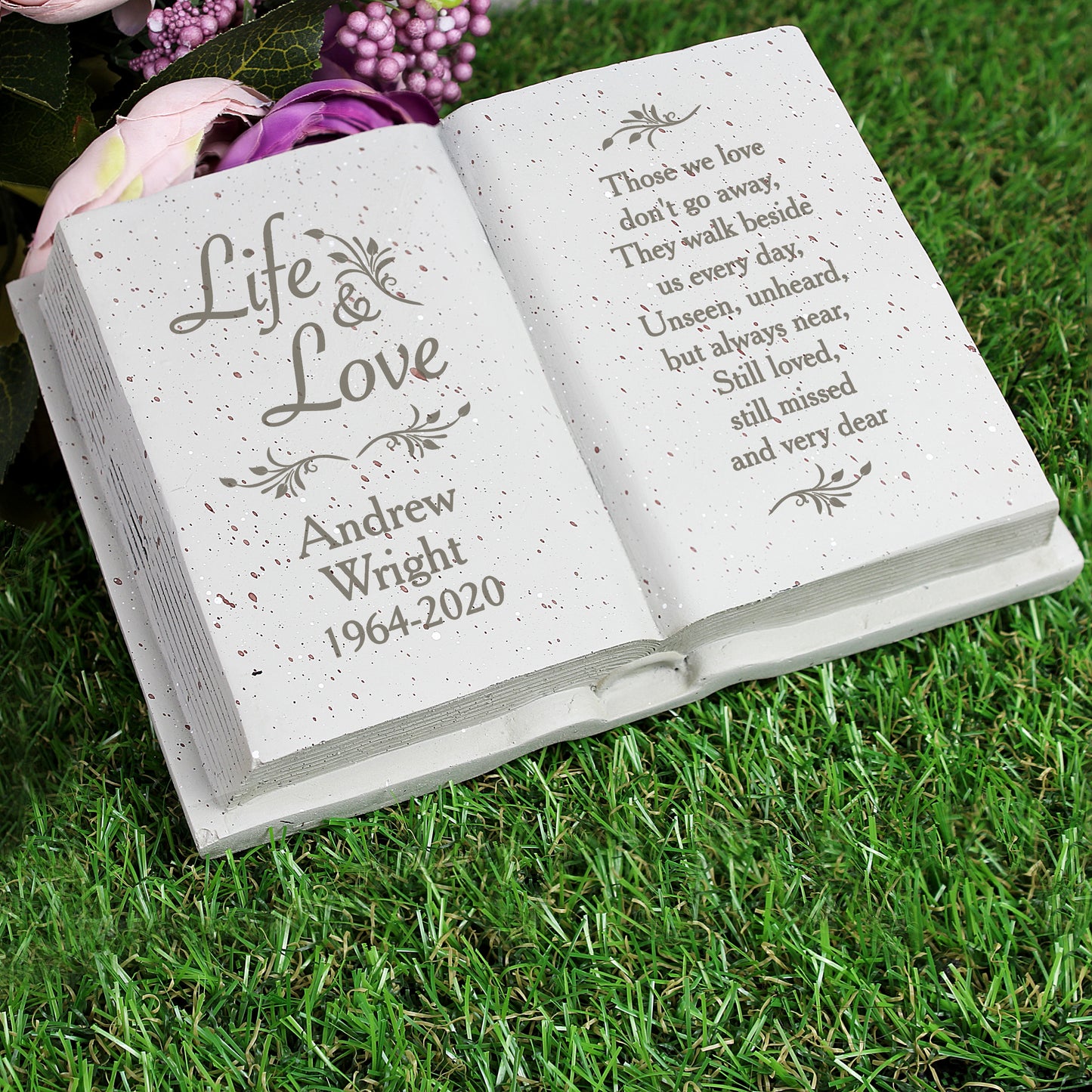 Memorial book with engraved text on a grassy background