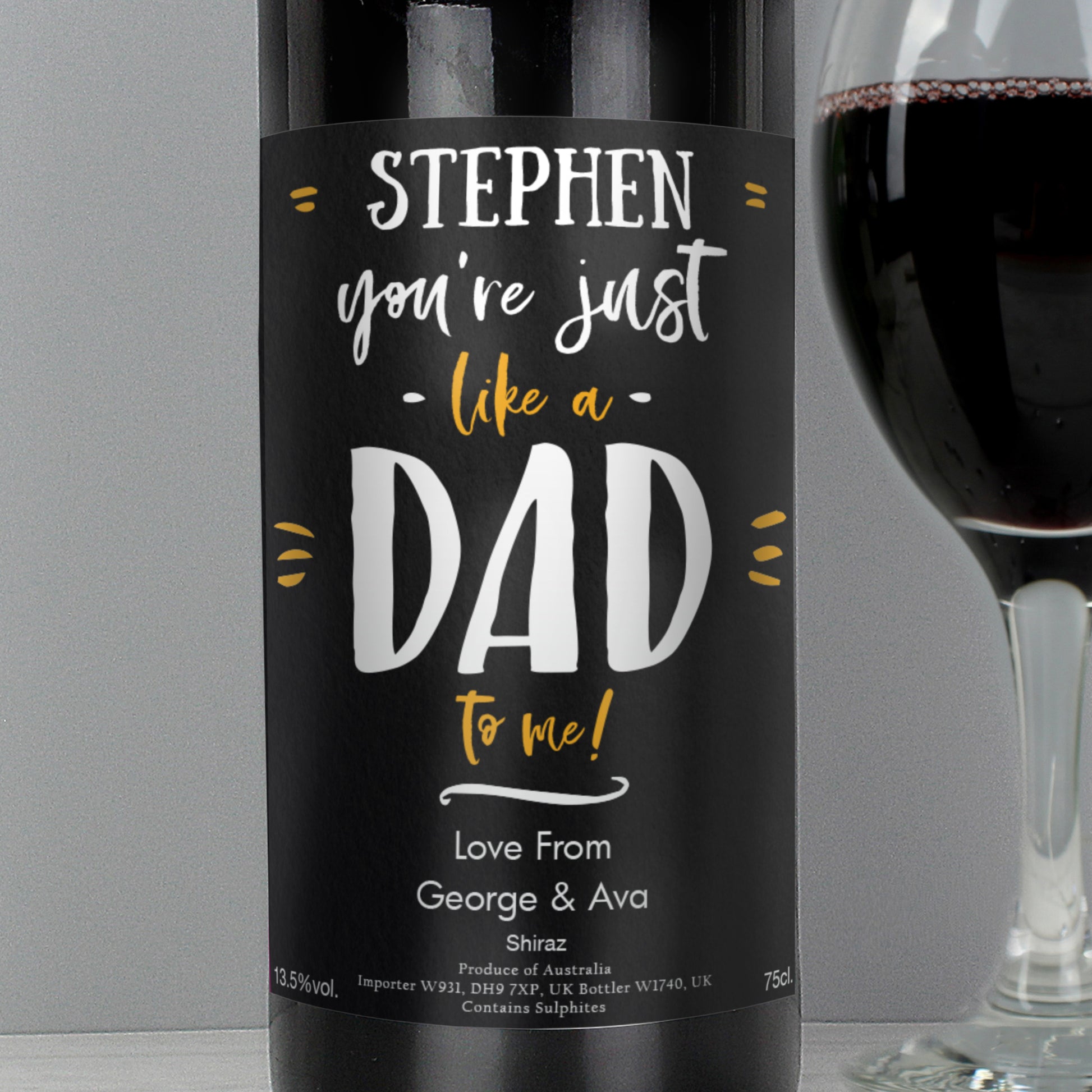 Wine bottle with personalised label reading 'Stephen, you're just like a dad to me! Love From George & Ava' next to a glass of wine.