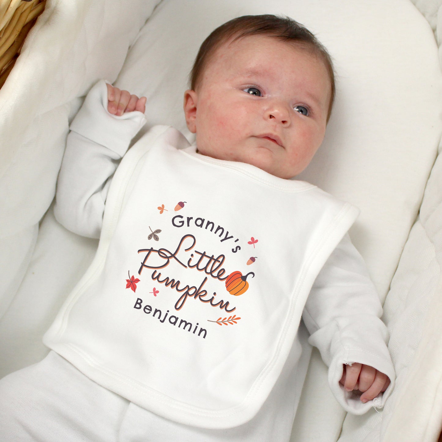 Baby wearing a bib with 'Granny's Little Pumpkin Benjamin' text
