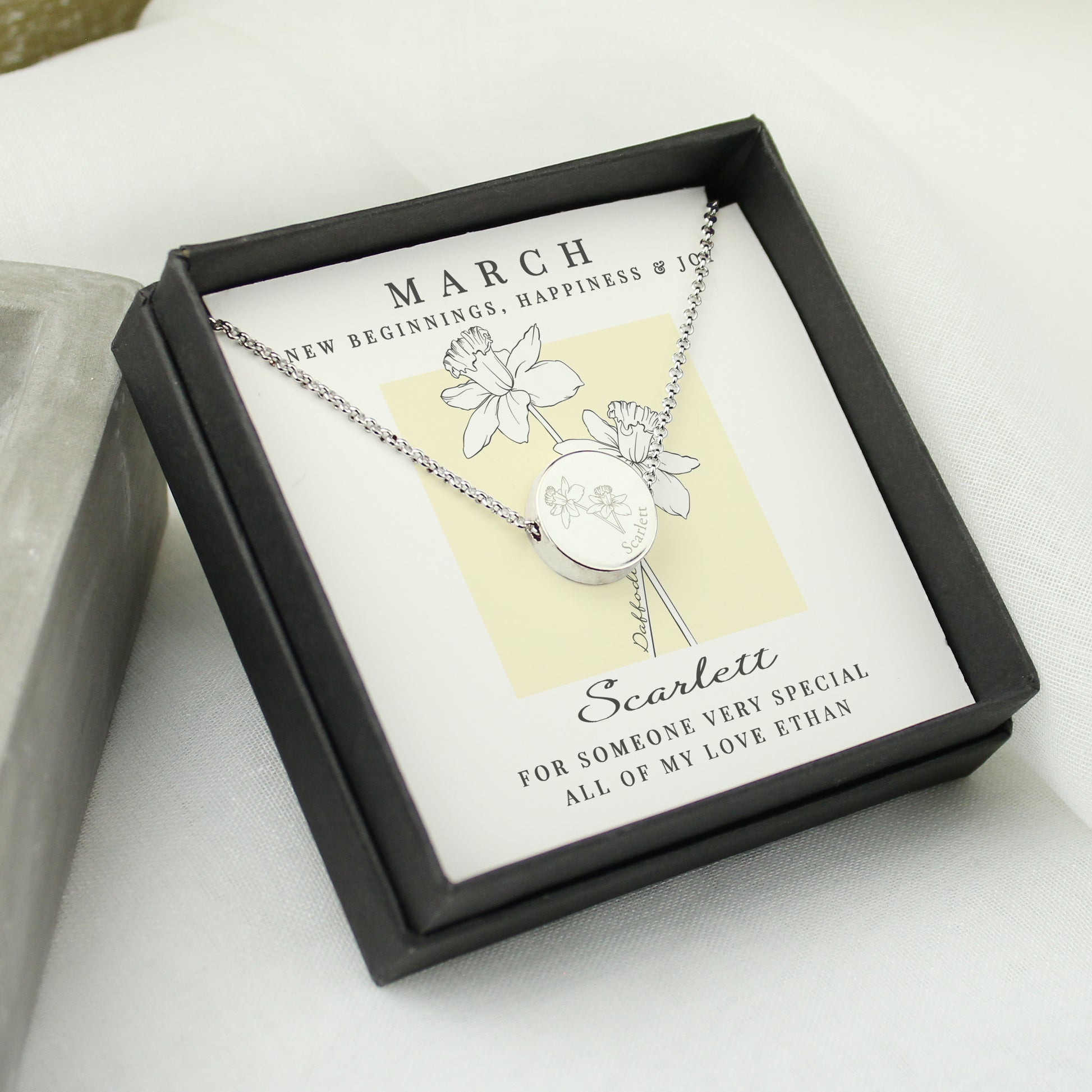 Silver necklace in a black box with a card detailing the month of birth and a message.