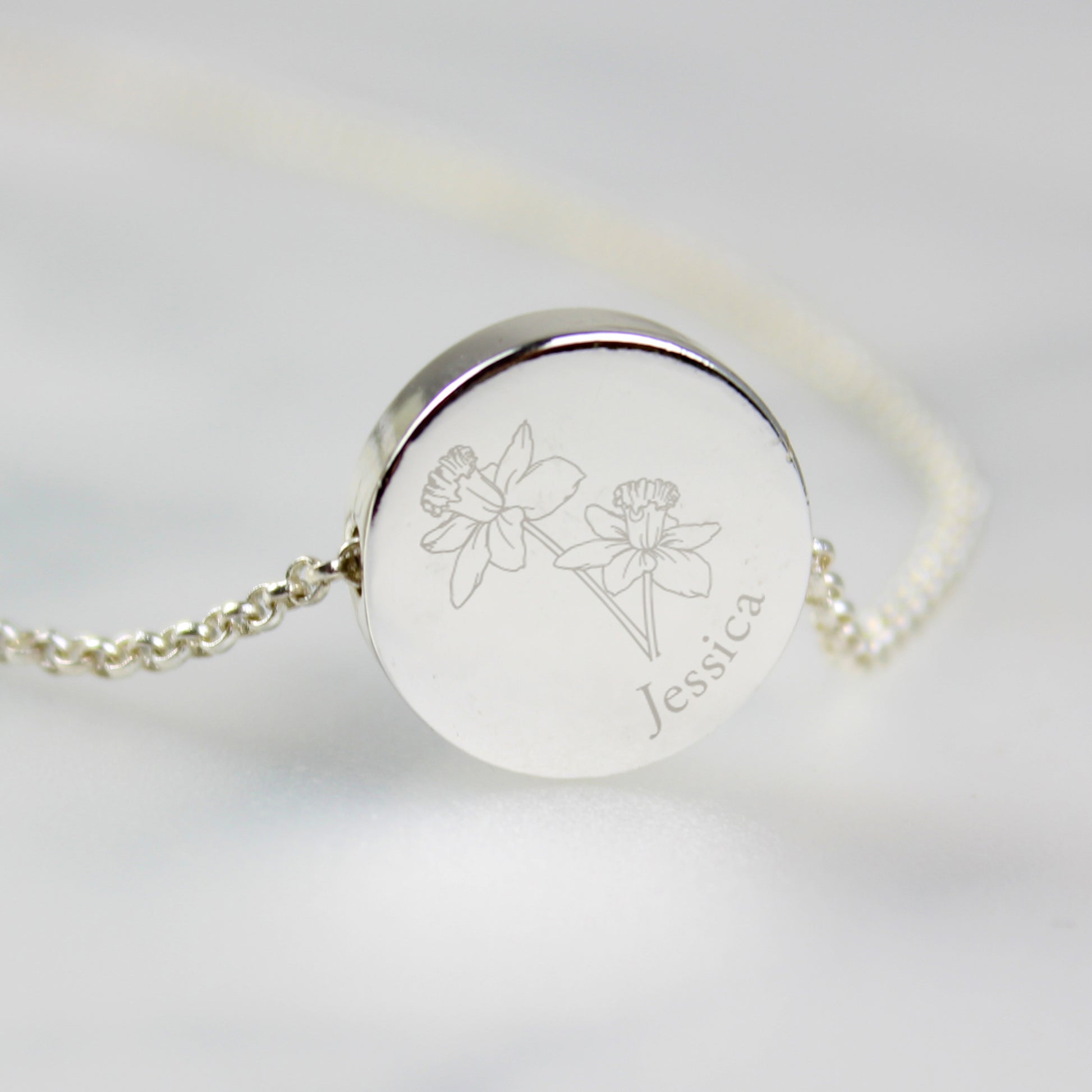 Silver bracelet with engraved floral design and name on a light grey background