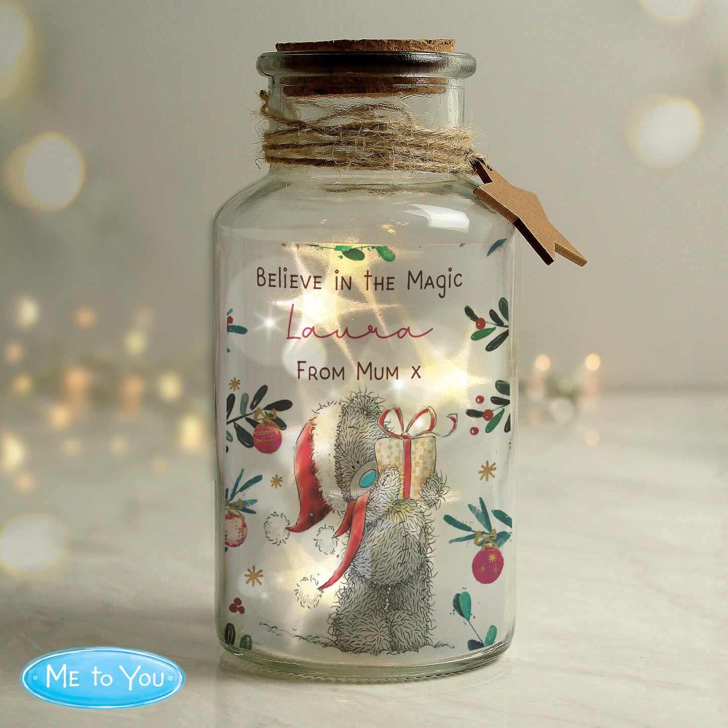 Decorative glass jar with LED lights featuring a bear illustration and text, on a soft blurred background.