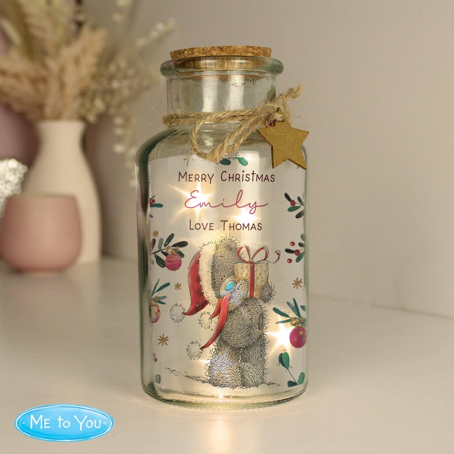 Decorative glass jar with a Christmas design featuring a bear and text, on a neutral background.