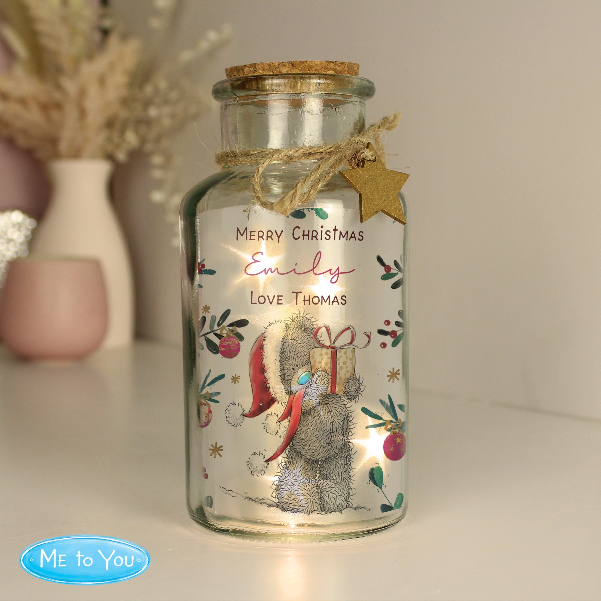 Decorative glass jar with a Christmas design featuring a bear and text, on a neutral background.