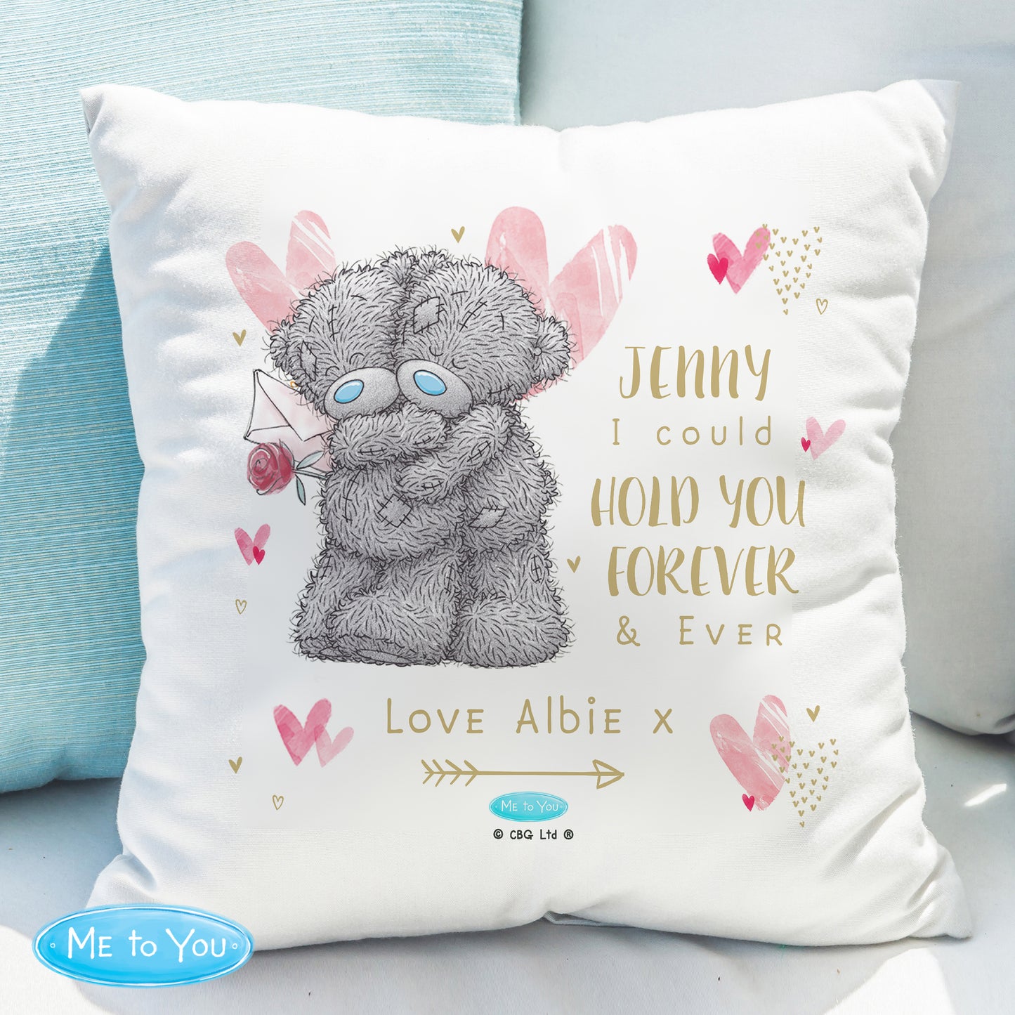 Cushion with teddy bear illustration and personalised text on a light blue sofa.