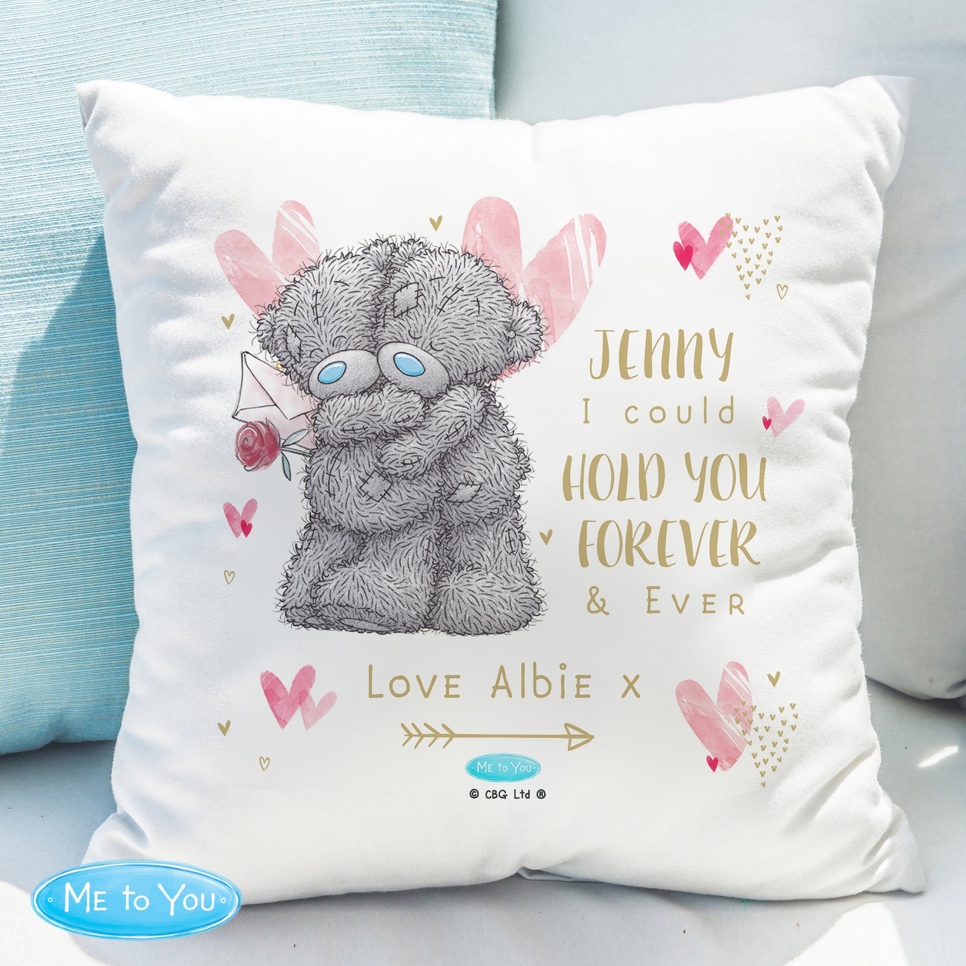 Cushion with teddy bear illustration and personalised text on a light blue sofa.