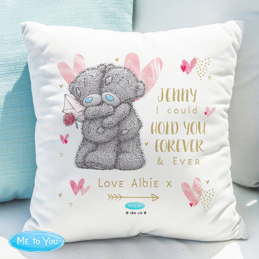Cushion with teddy bear illustration and personalised text on a light blue sofa.