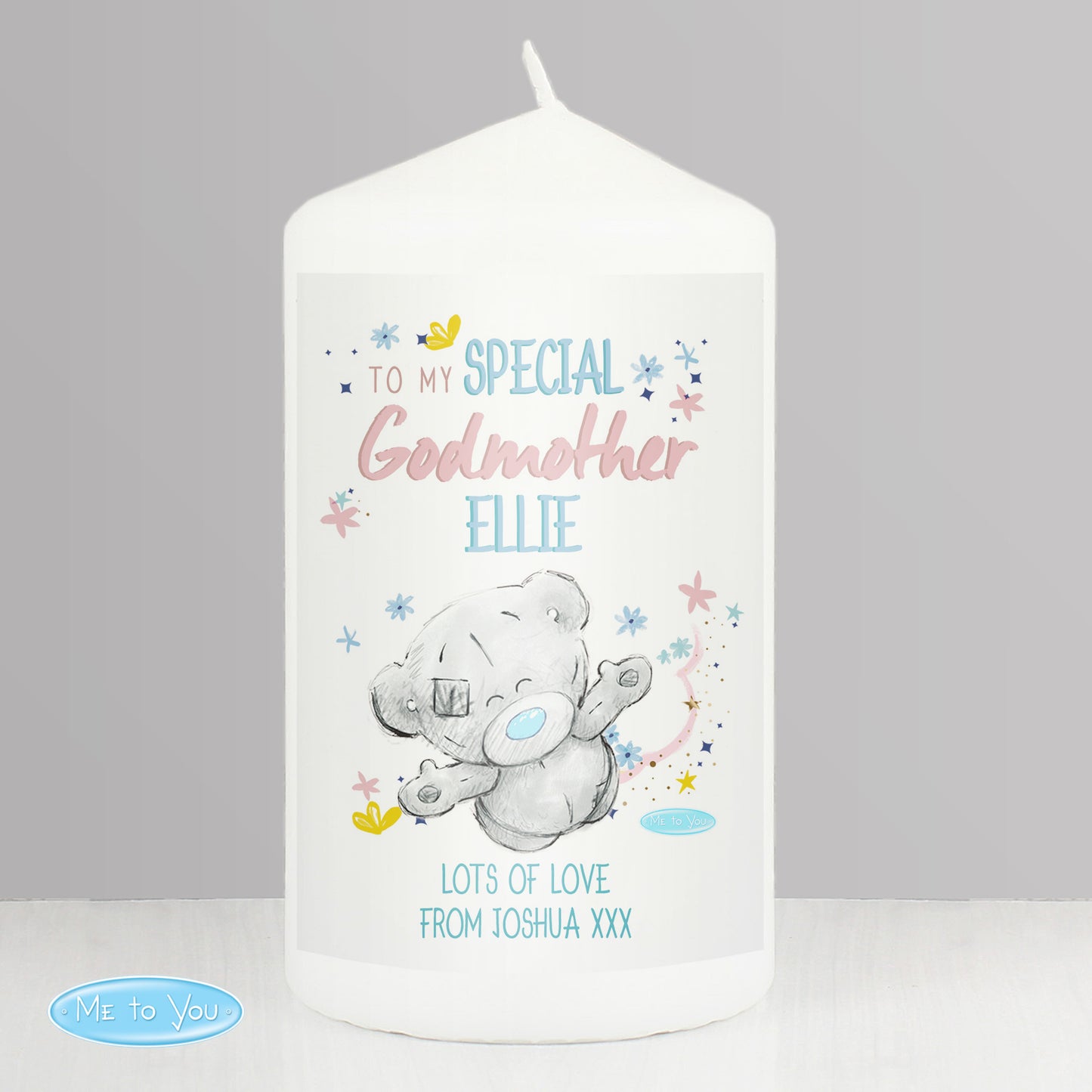 White candle with a teddy bear design and personalised text on a grey background