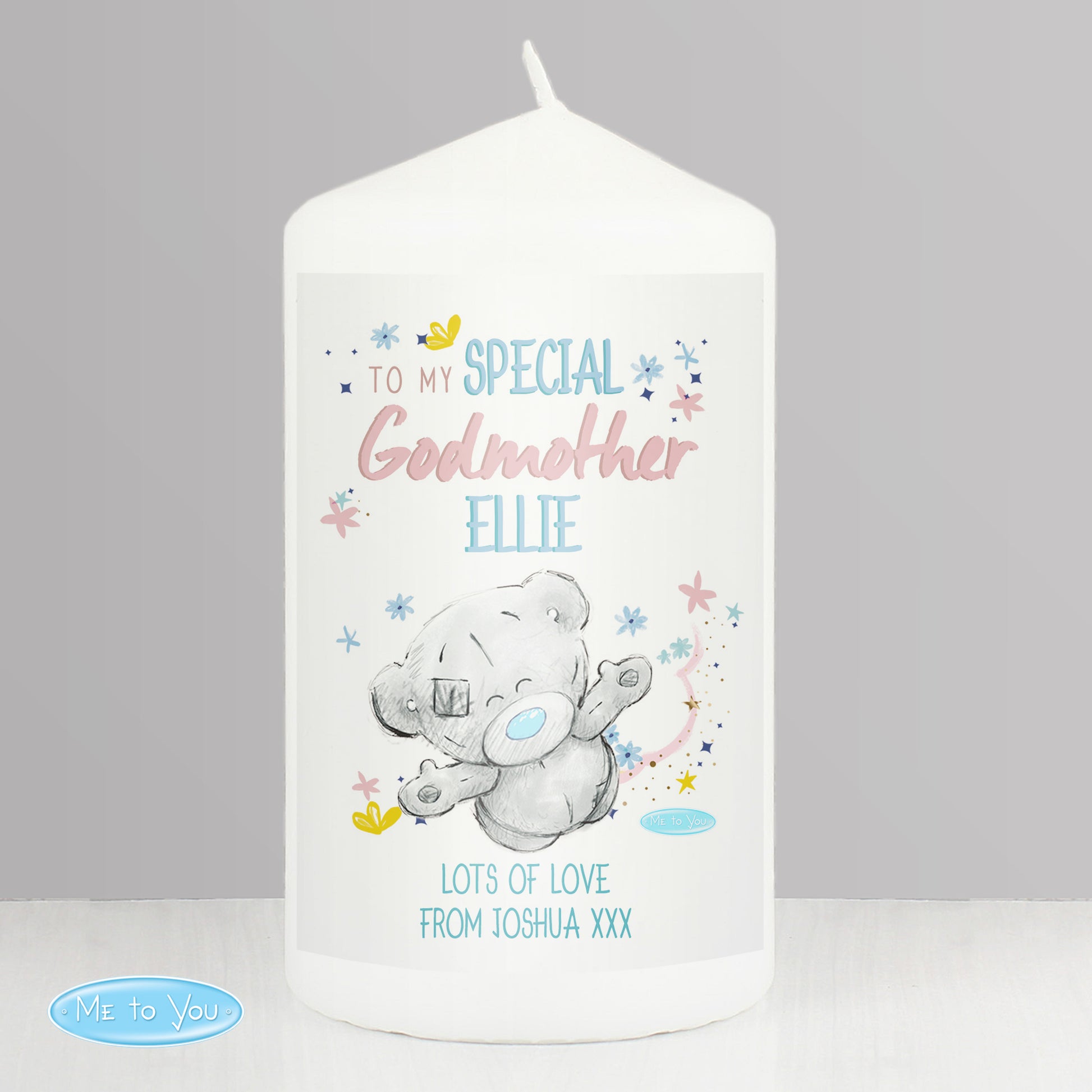 White candle with a teddy bear design and personalised text on a grey background