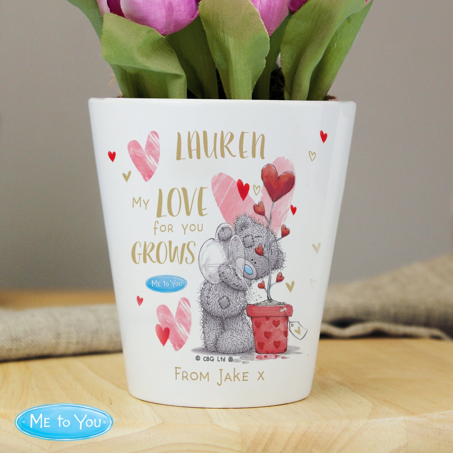 Personalised plant pot with teddy bear design and floral arrangement on a wooden surface