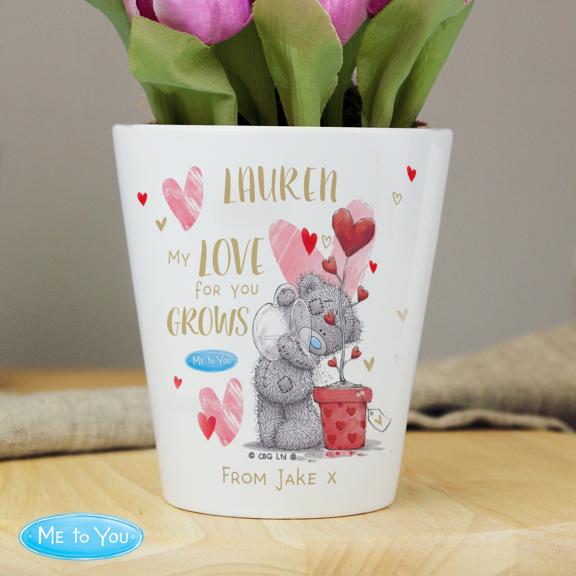 Personalised plant pot with teddy bear design and floral arrangement on a wooden surface