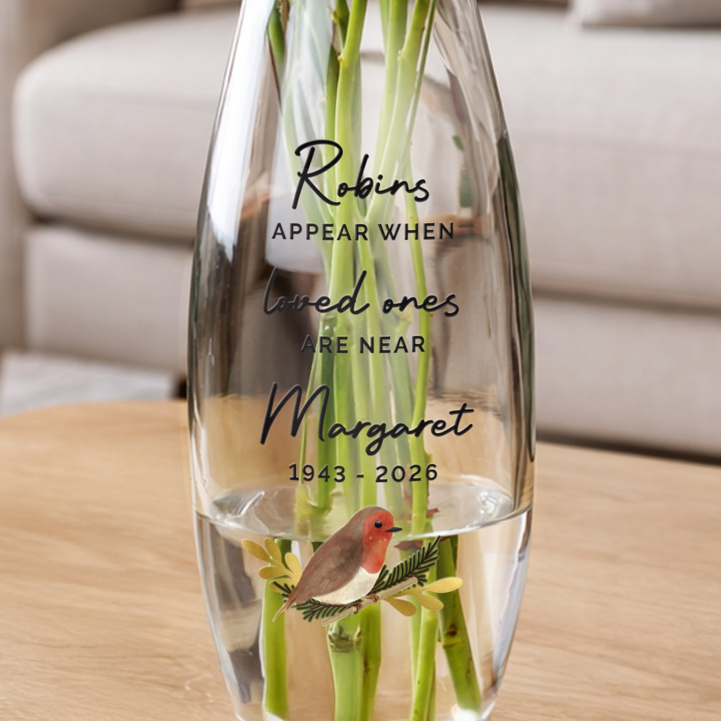 Clear glass vase with engraved text and a robin illustration on a wooden surface.