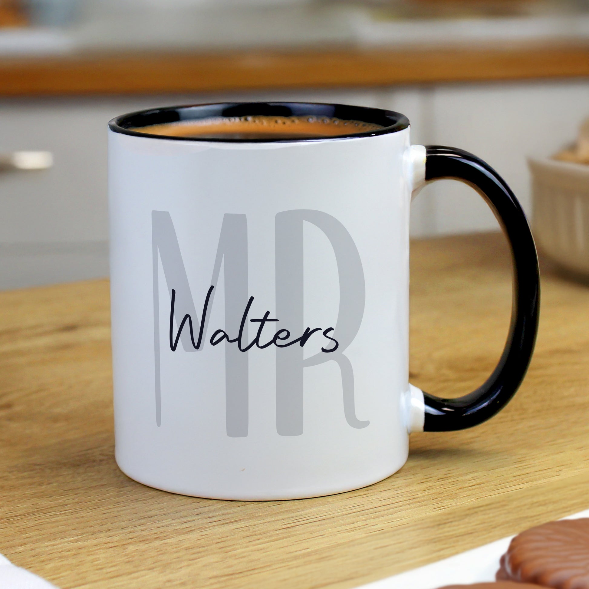 White mug with black interior and handle, featuring 'MR Walters' text, on a wooden surface.