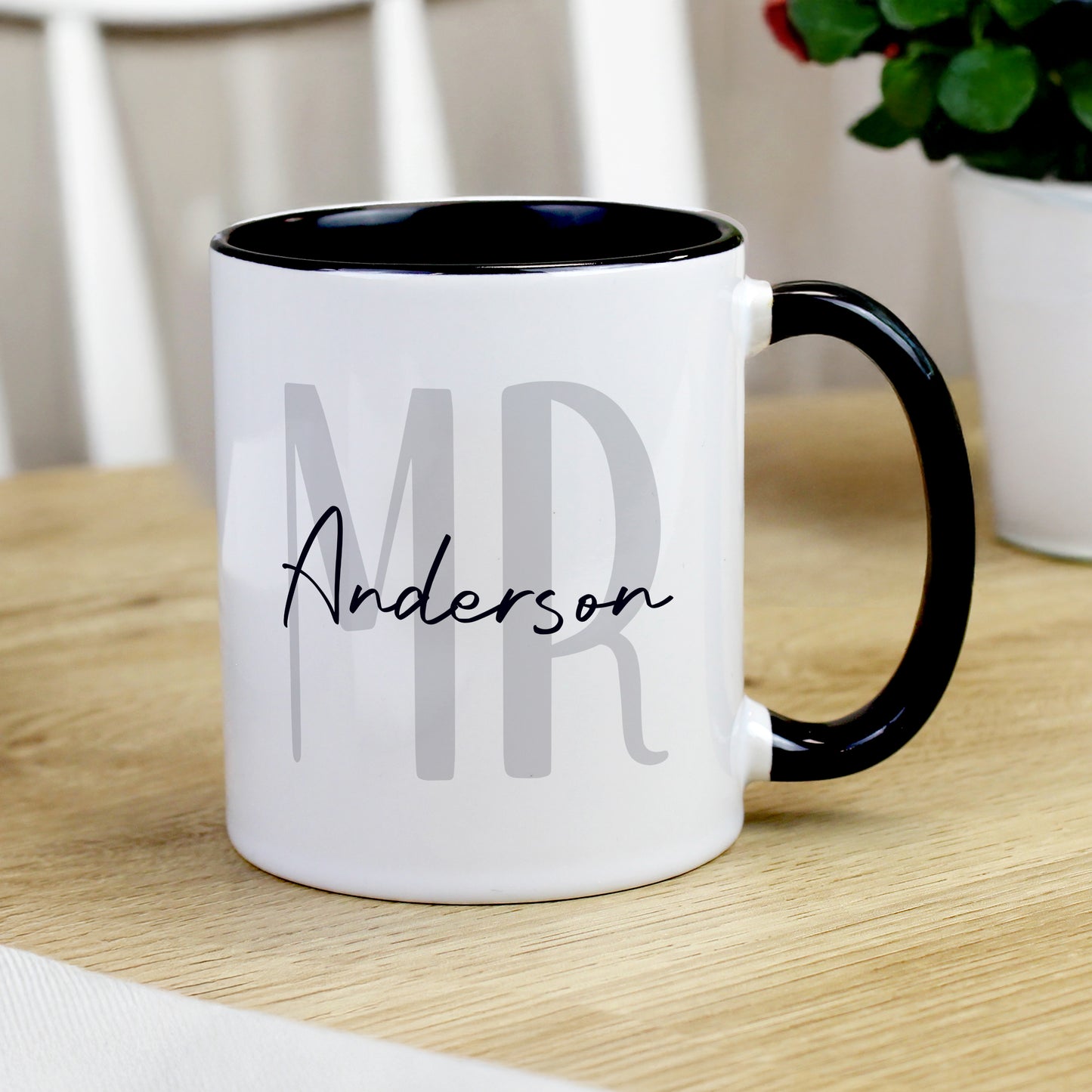 White mug with black interior and handle, featuring 'MR Anderson' text, on a wooden surface.