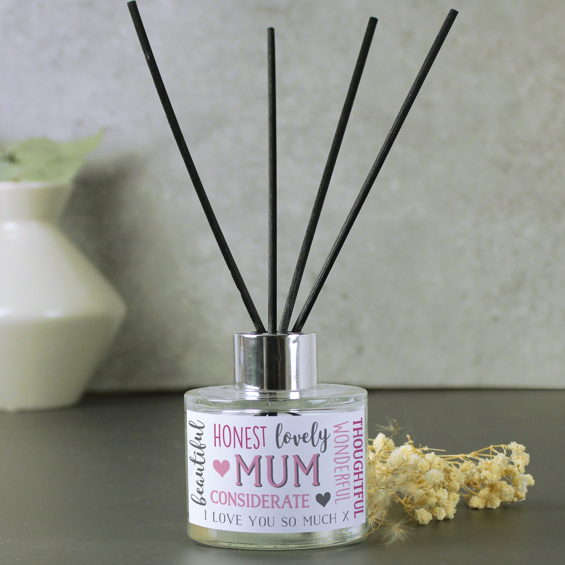 Reed diffuser with decorative label on a neutral background