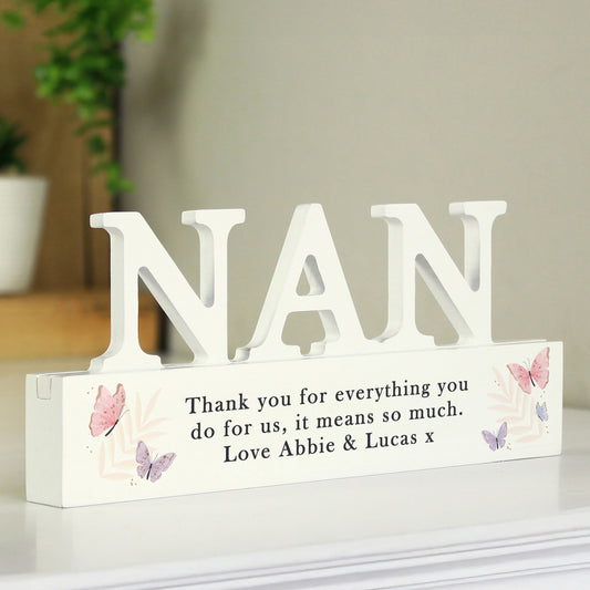 White decorative sign with 'NAN' and a message on a white surface.