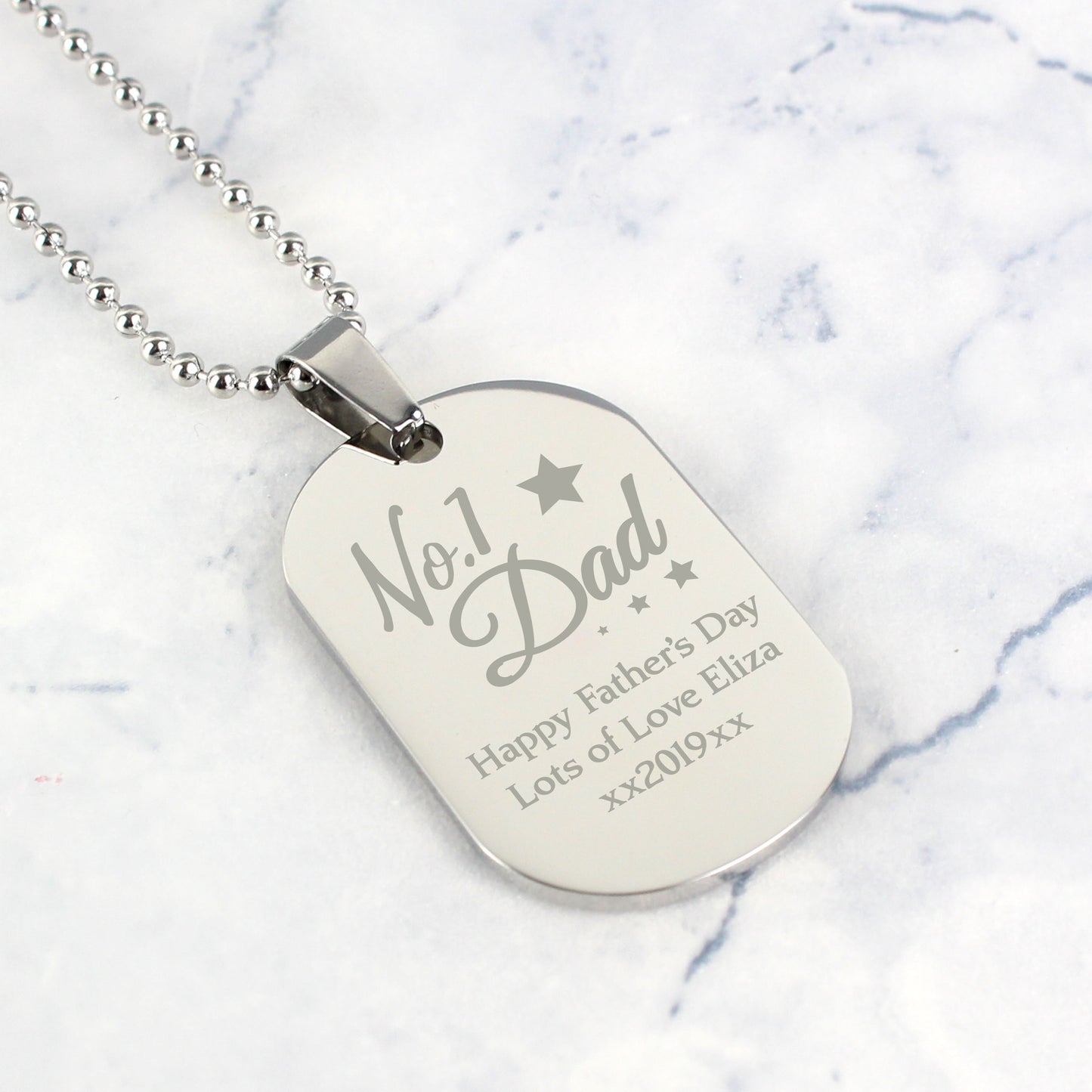 Silver dog tag necklace with engraved text on a marble background