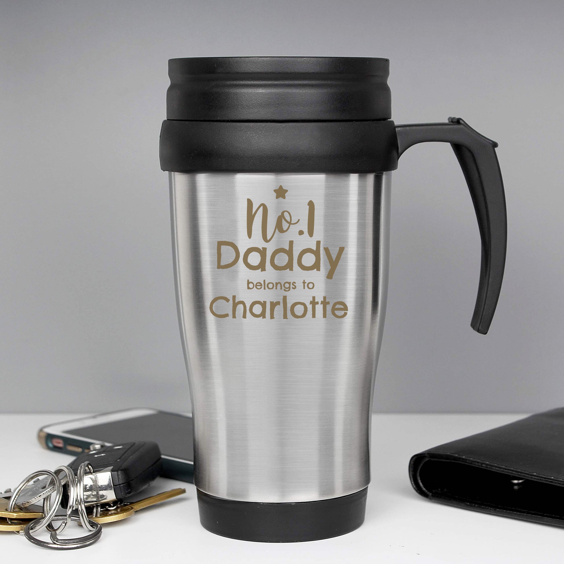 Silver travel mug with black handle and lid, featuring 'No.1 Daddy belongs to Charlotte' text, on a grey background.