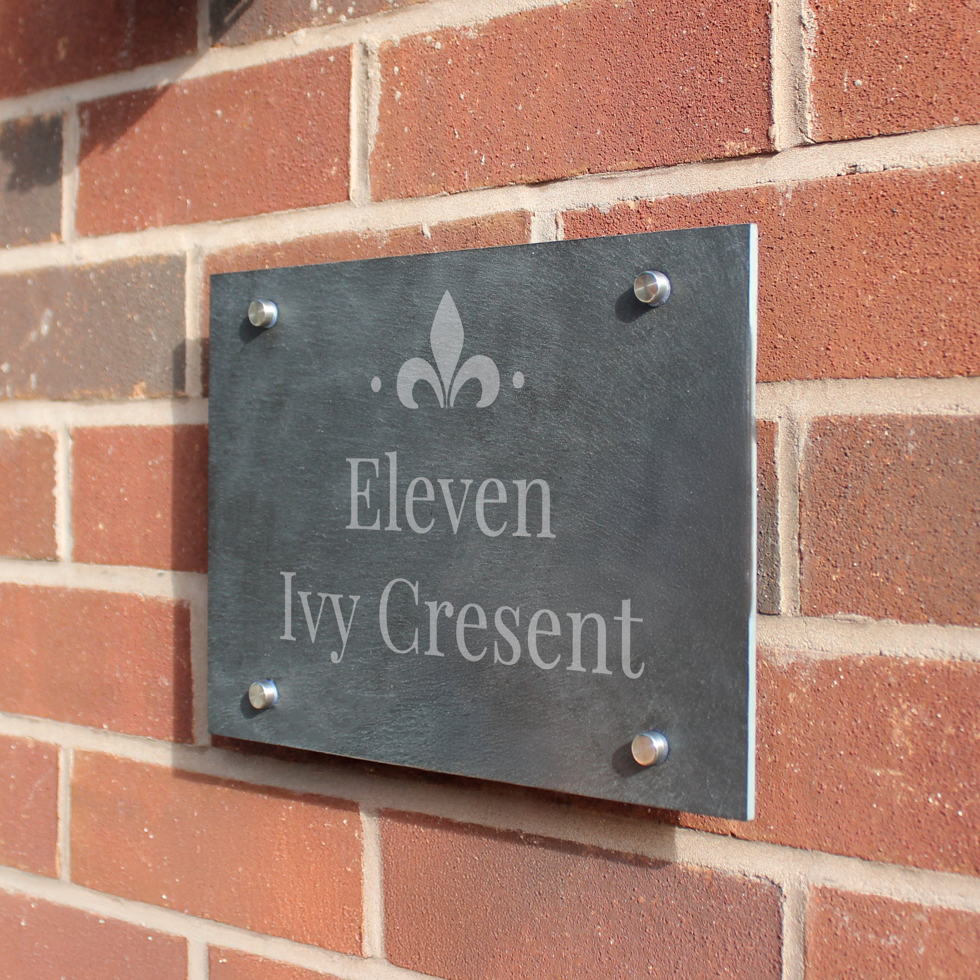 Slate house sign with 'Eleven Ivy Crescent' on a brick wall