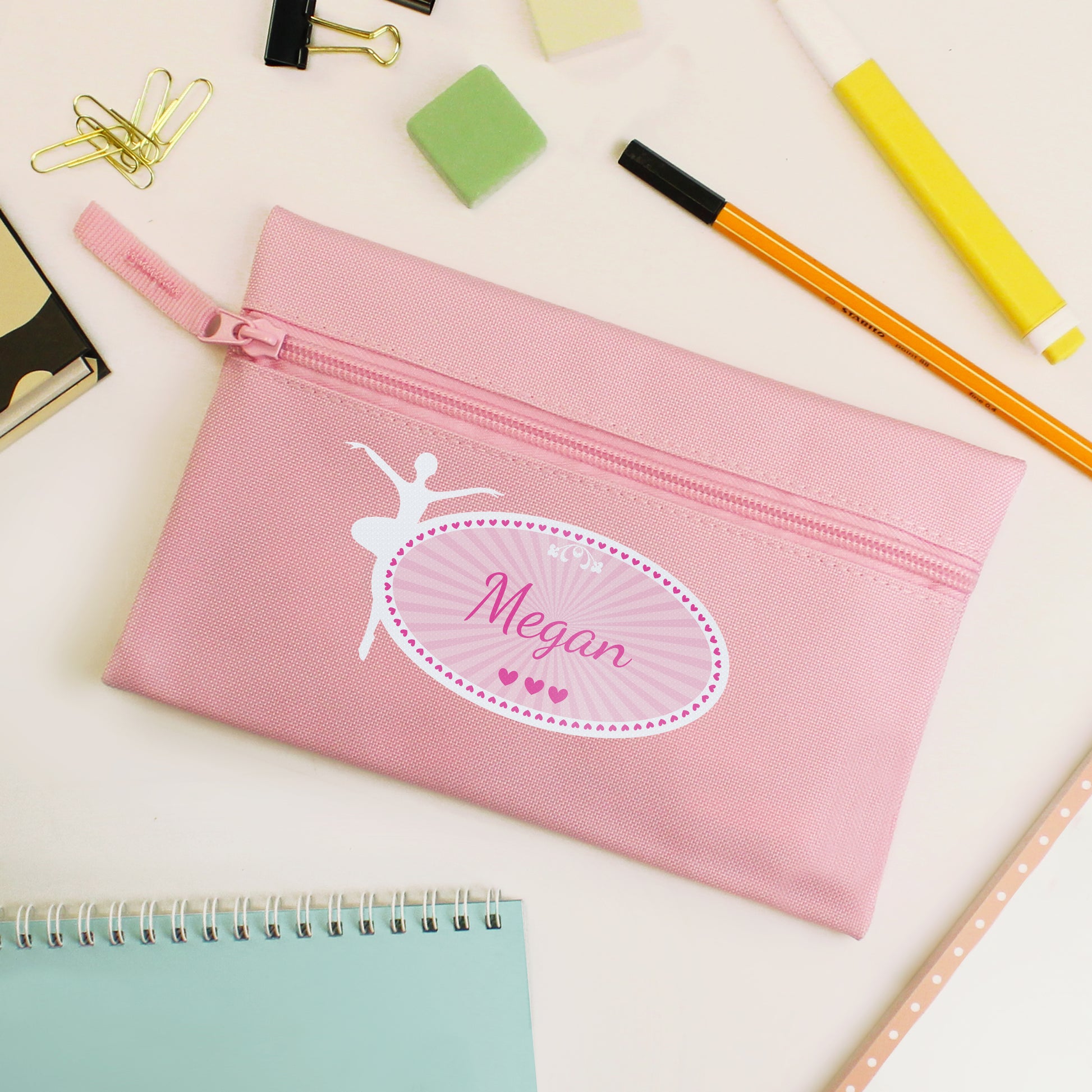 Pink pencil case with 'Megan' and a ballerina design on a desk with stationery items.