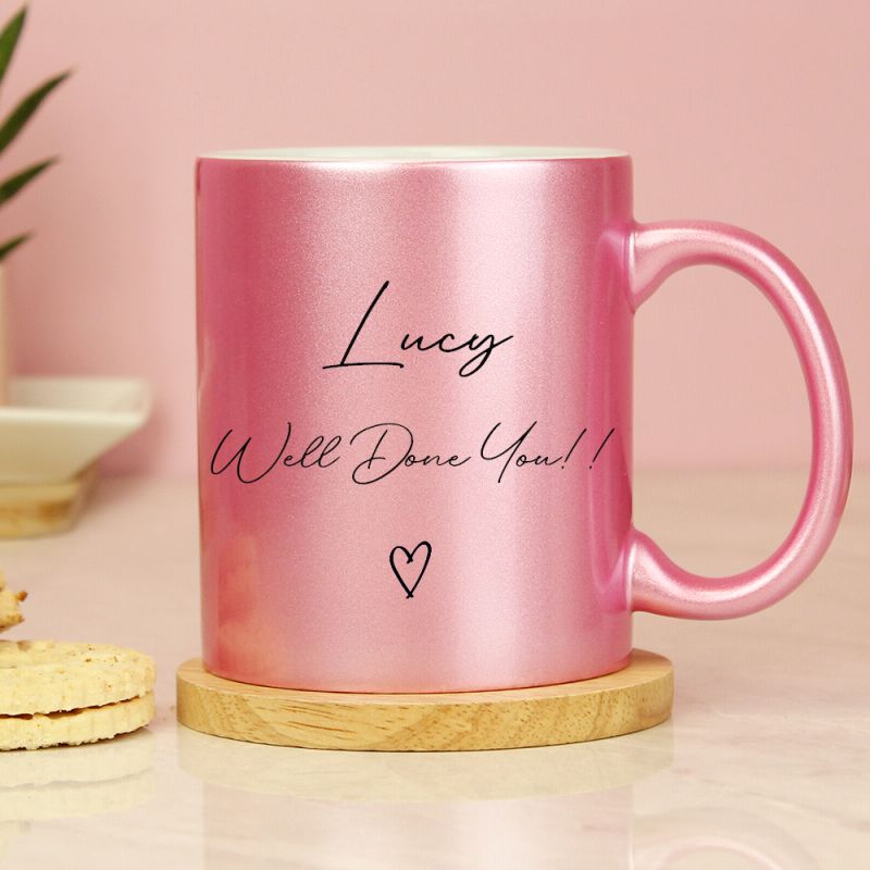 Pink glitter mug with personalised graduation details. Shown on a wooden coaster ( not included).